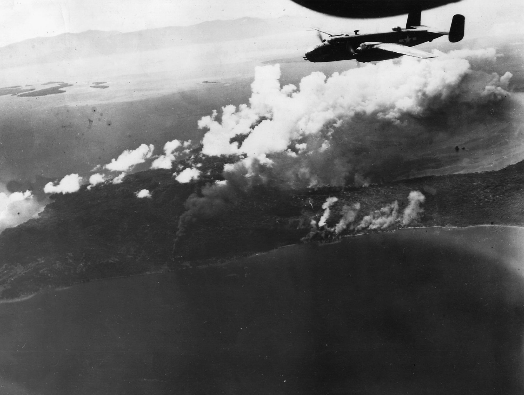 A B-25 of the Thirteenth Air Force roars over burning Japanese oil installations in New Britain.