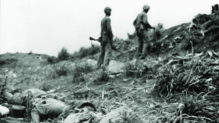 The carnage of the battle for Iwo Jima is evident in this photograph showing two American soldiers making their way past some of the fatalities. (National Archives)