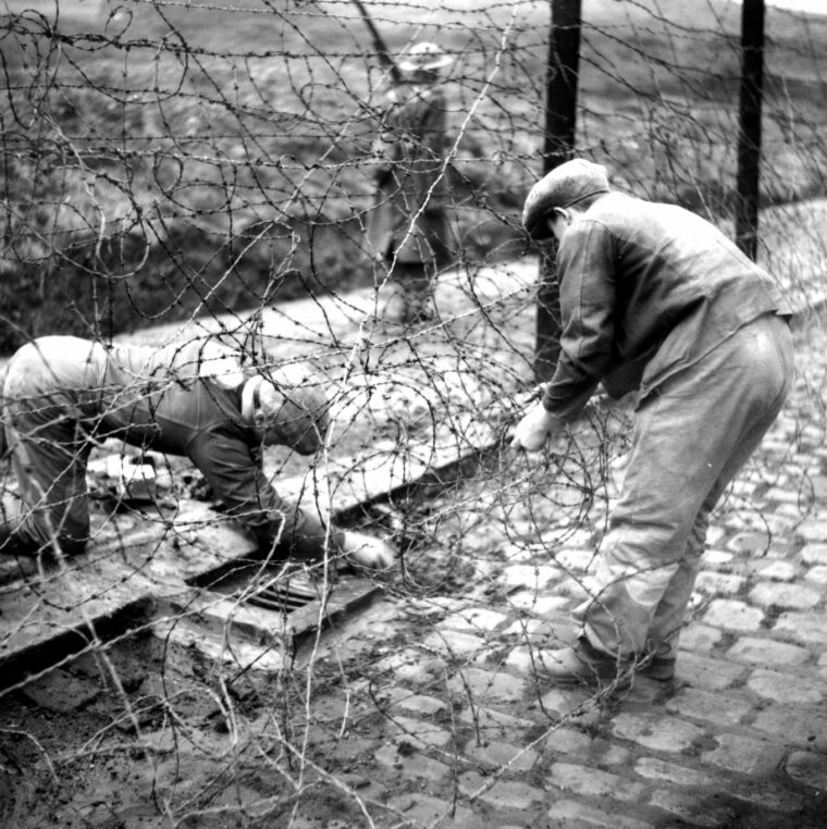 German prisoners of war labor to repair a damaged barbed wire fence at the Glen Mill camp following the abortive escape attempt of December 1944.