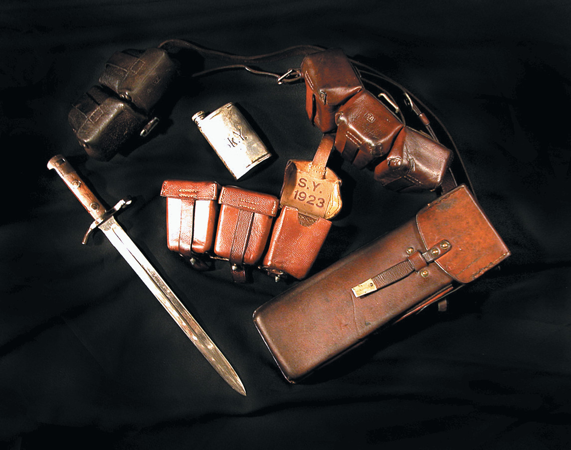 A collection of Finnish militaria includes a Russian two-pocket ammo pouch (top left), a Finn Civil Guard Model 28 bayonet (left), a Civil guard Sk.Y. stamped rifle oiler (center, top), a WWI German three-pocket ammo pouch (center, bottom), a second WWI German three-pocket ammo pouch (top right), and a 1925 Civil Guard submachine gun magazine pouch.