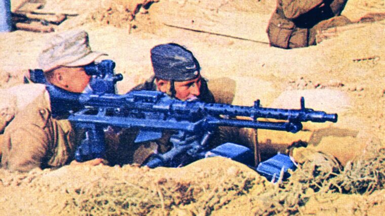 German troops man a real tripod- mounted MG-34 machine gun fitted with long-range sights.