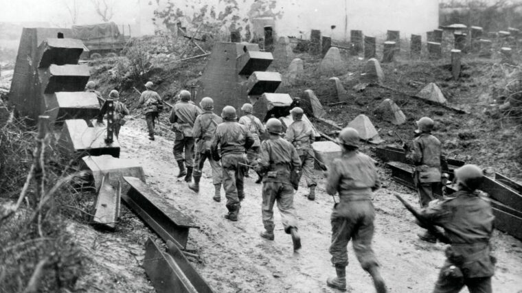 Because retreating German forces had to be able to pass through their own Siegfried Line, passageways such as this one, which had steel girders blocking the gap, were necessary. Here, men of Company E, 358th Regiment, 90th Infantry Division, move unhindered through one of these gaps, January 12, 1945.
