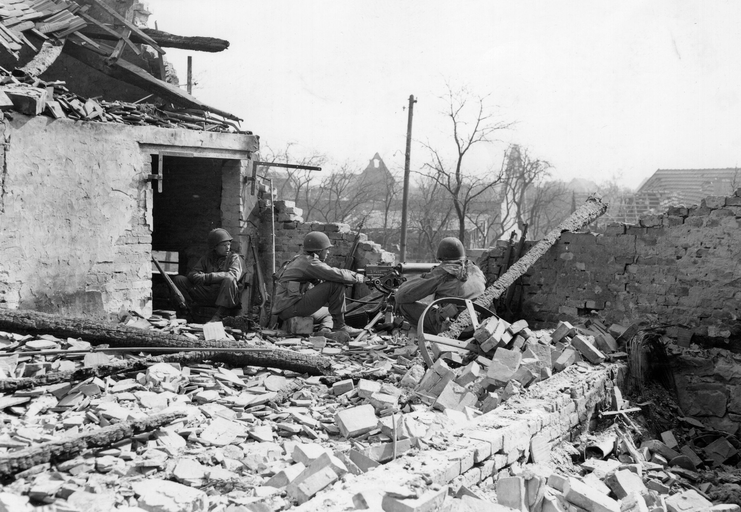 An American machine-gun team sets up a position in the shattered ruins of a building facing the defenses of the Siegfried Line.