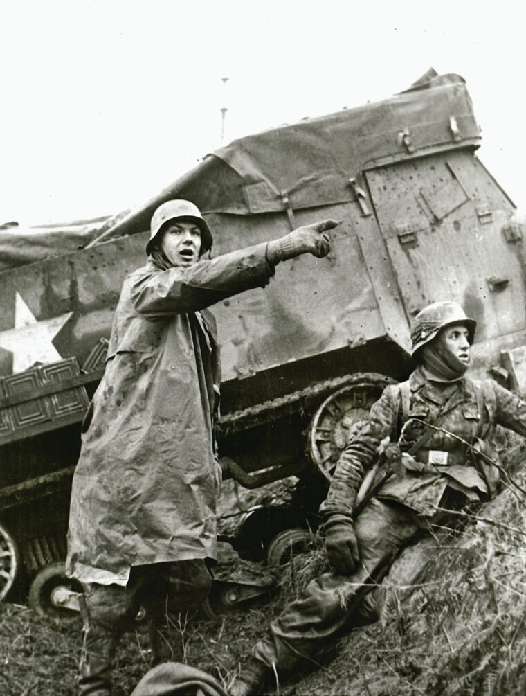 A German officer of the 2nd SS Panzer Division, dressed in a captured American raincoat, gestures beside a disabled American halftrack during the Battle of the Bulge, December 1944. After conferring with his superiors, General Patton took decisive action to halt the German advance.