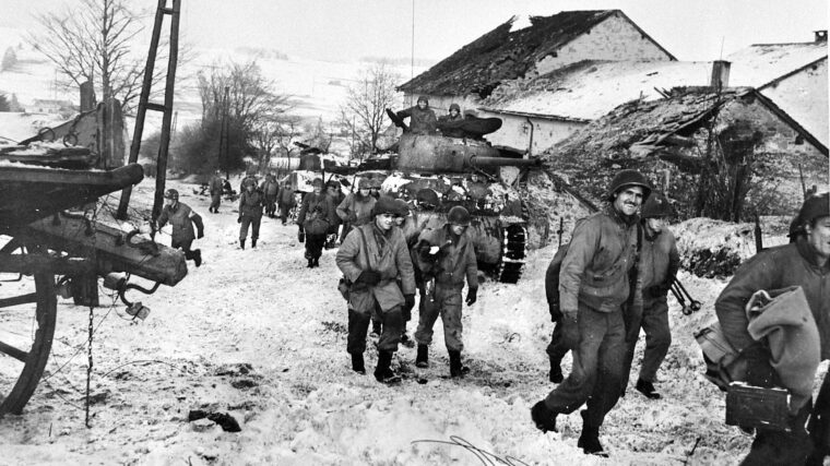 Despite being cold and weary, some reconnaissance troops of the 87th Infantry Division (Patton’s Third Army) can smile as they march through Bihain, Belgium, to attack German troops dug in beyond the town, January 1945.
