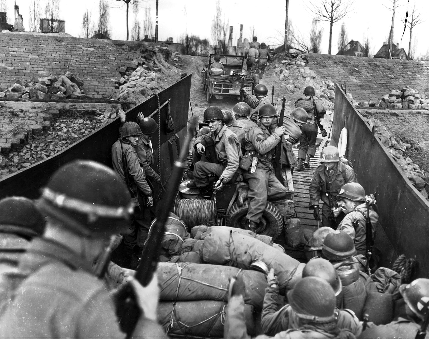 Men and vehicles of the 80th U.S. Infantry Division load into Coast Guard-operated landing craft on the west side of the Rhine prior to making the crossing. The U.S. Navy and Coast Guard were instrumental in transporting troops over the river.