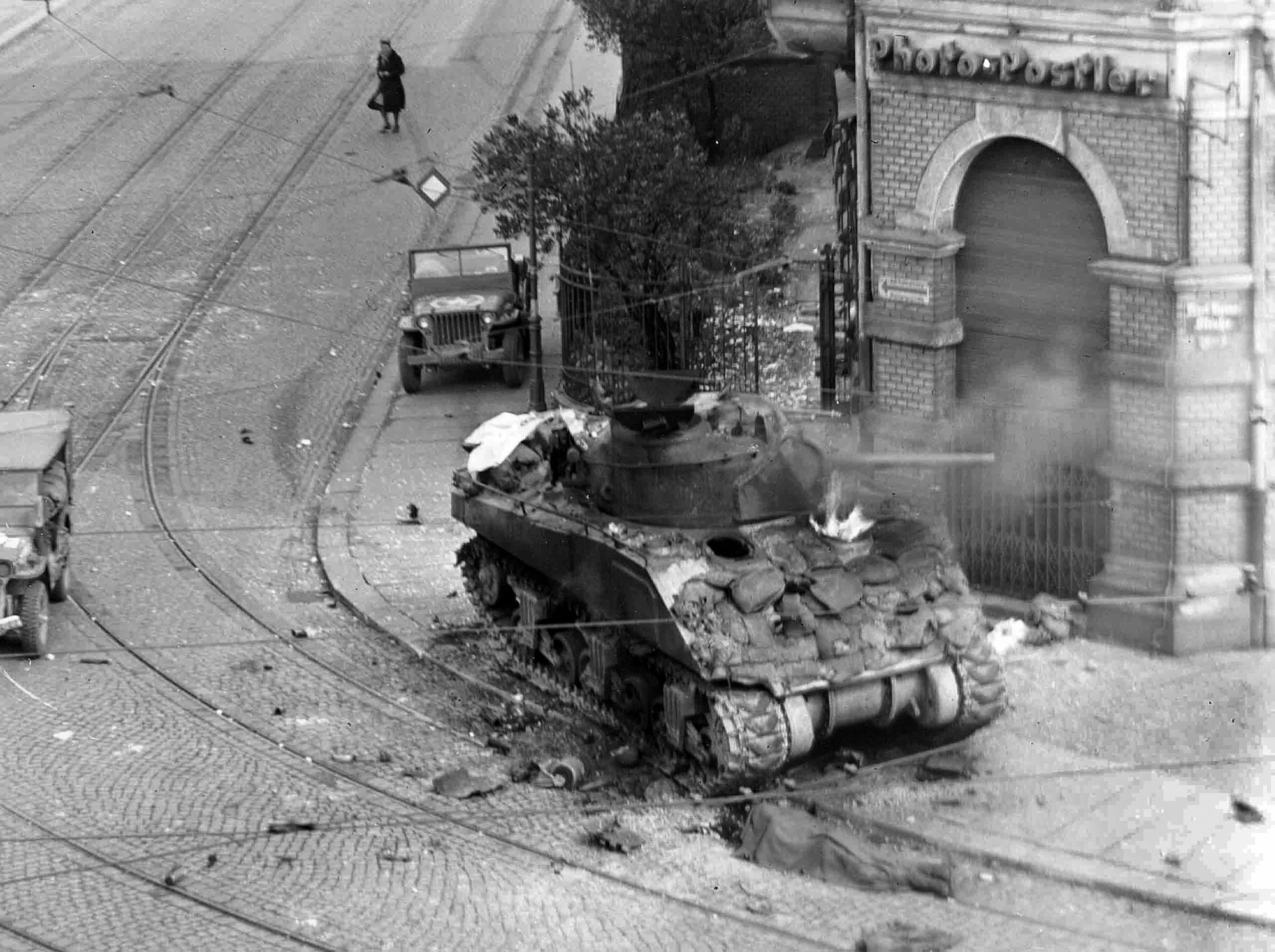 A German panzerfaust anti-tank weapon, operated by Hitler Youth members, has knocked out this Sherman tank and set it ablaze in the center of Leipzig, Germany, April 1945. The hit devastated the crew inside and created a pyschologically difficult job for the maintenance personnel.