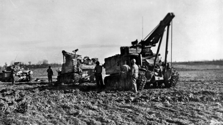 Armored recovery vehicles (ARVs) retrieve a damaged tank near Beggendorf, Germany. ARVs were typically built on a tank chassis and hoisting cranes in place of a gun turret.