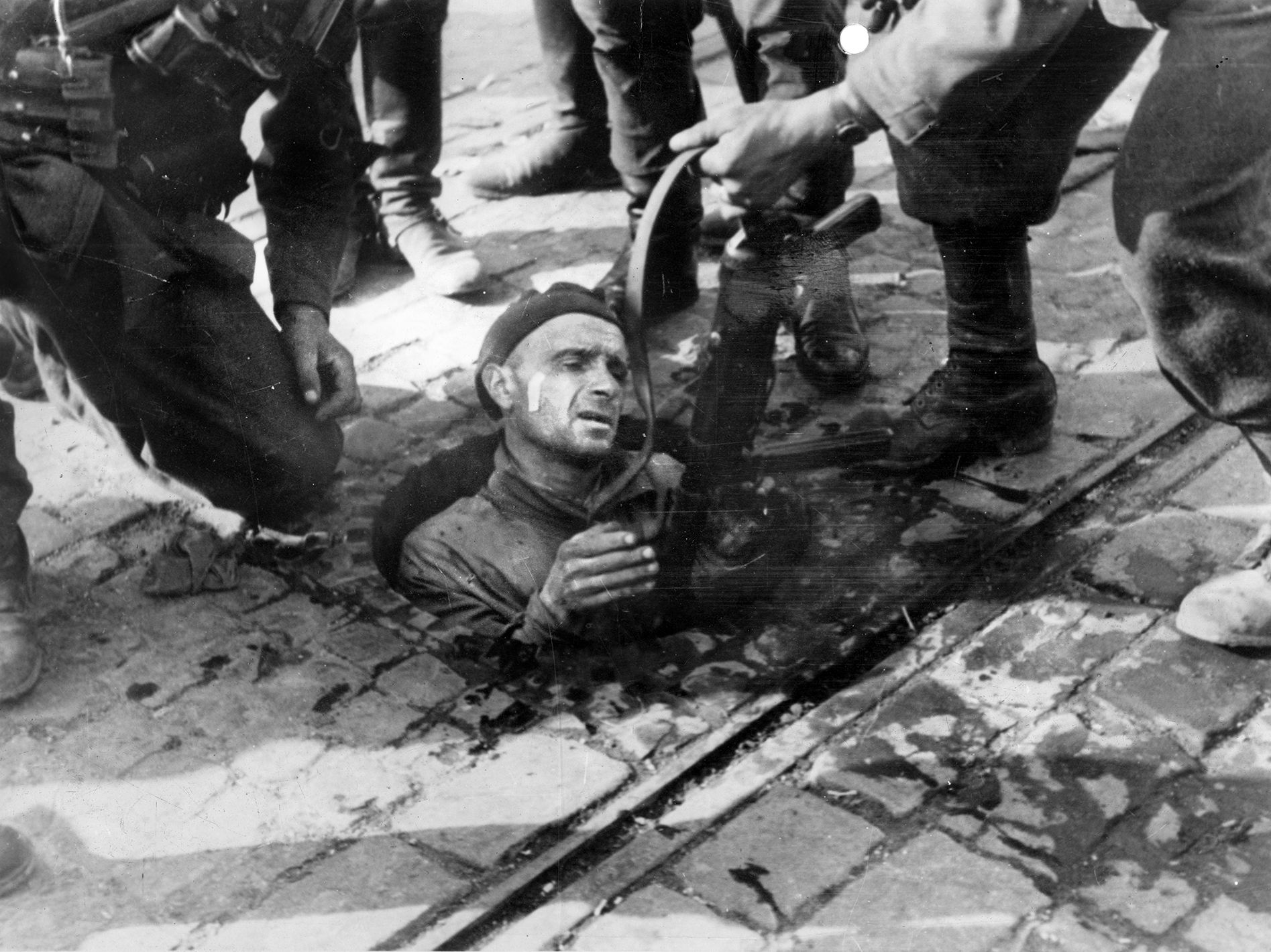 A Polish fighter is pulled from his hiding place in a sewer and taken prisoner by German soldiers. He was probably executed.