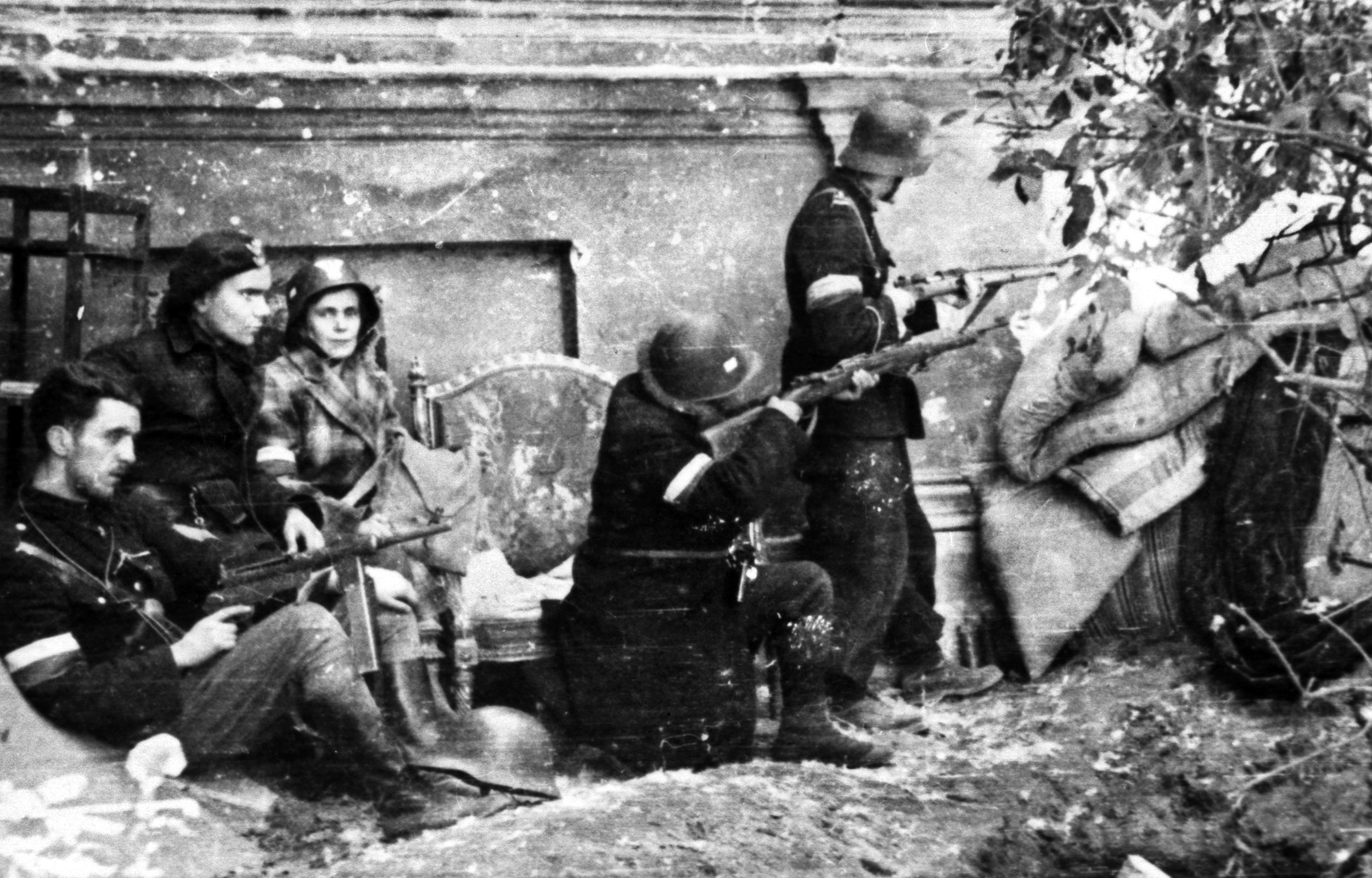 Four men and a woman of Warsaw’s Milosz Battalion man an improvised barricade against a German assault. Wearing a mixture of Polish and German uniforms, the fighters are also wearing red-and-white armbands—the colors of the Polish flag.