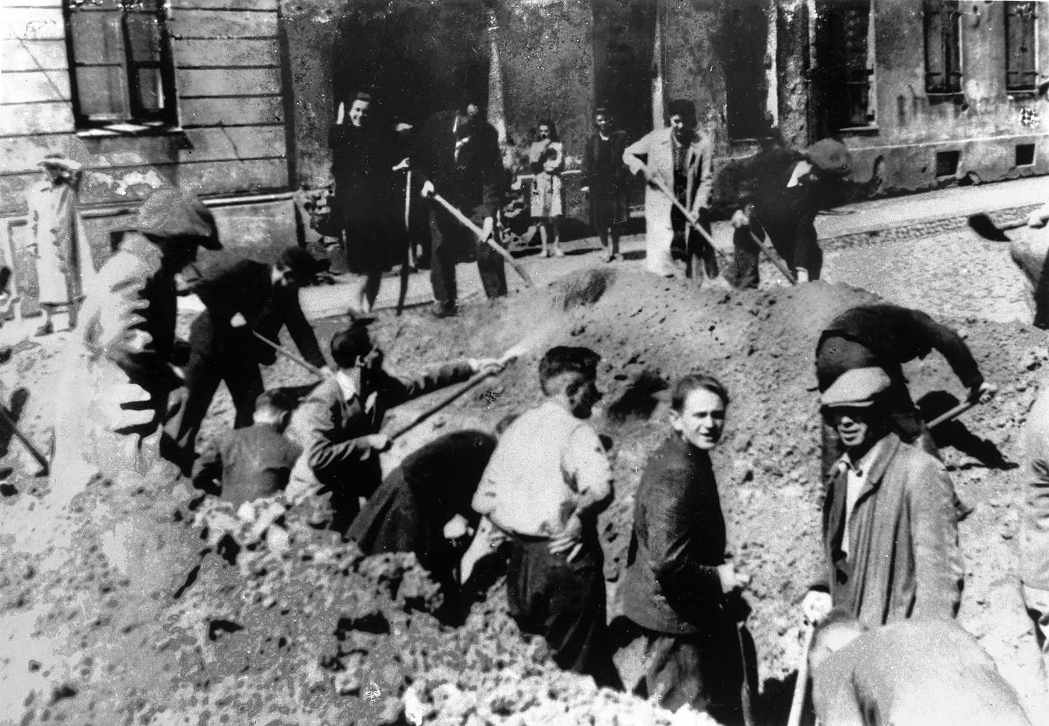 To ward off a panzer attack, Warsaw citizens dig an anti-tank trench in a street in the Wola District.