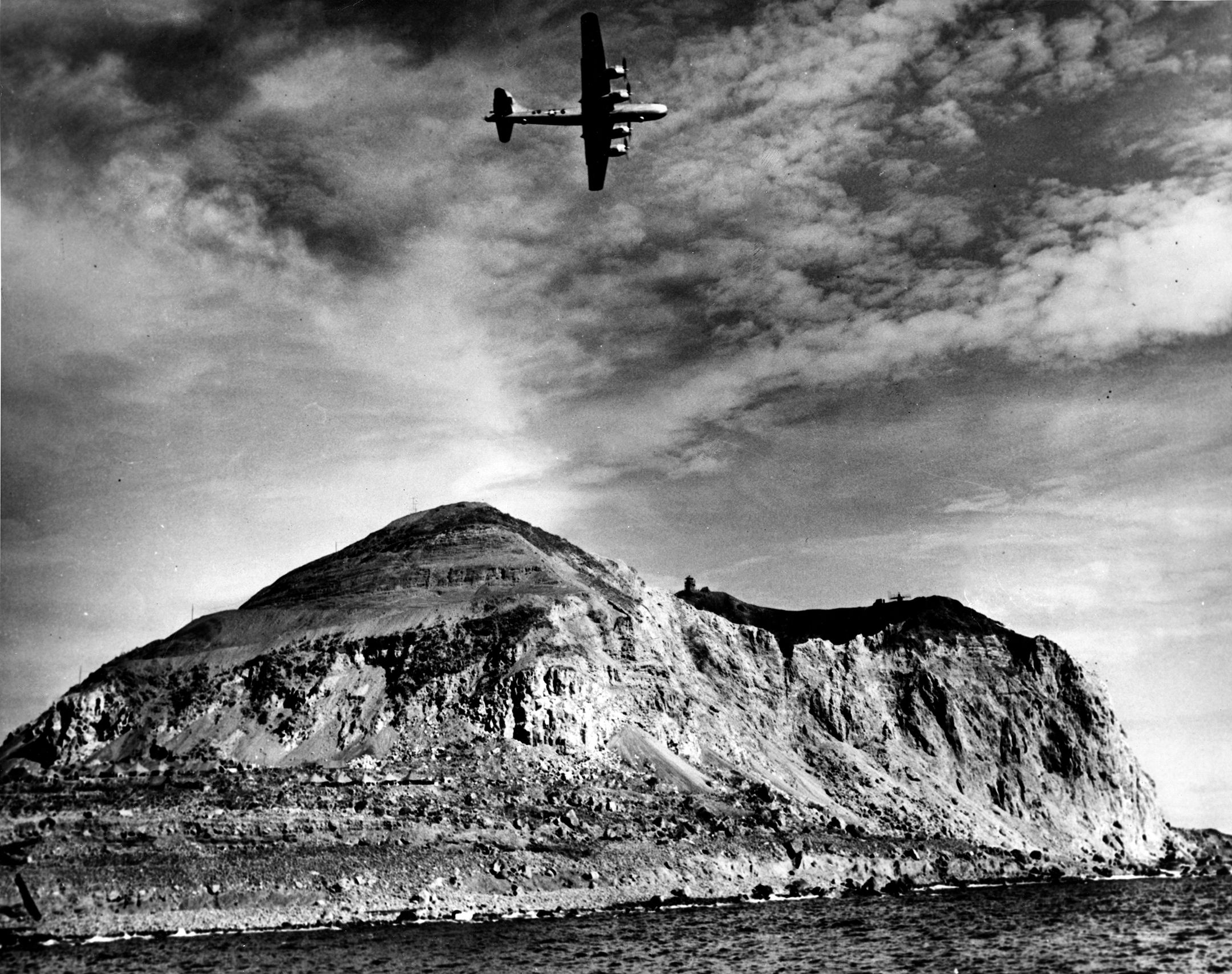 A Boeing B-29 Superfortress bomber of the U.S. 20th Air Force flies over Mount Suribachi on the island of Iwo Jima. Army Air Forces B-29s based in the Marianas Islands raided Japanese cities from 1944 until the end of World War II. 