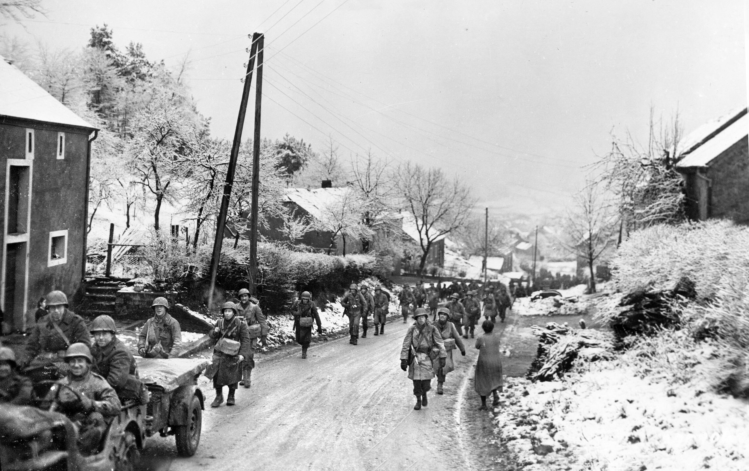 This photo was taken on December 23, 1944, during the rapid movement of Third Army toward Bastogne and the city of Echternach, Luxembourg, at the height of the Battle of the Bulge. These troops are Americans of the 101st Infantry Regiment, 26th Division moving through the town of Hobsheid, Belgium.