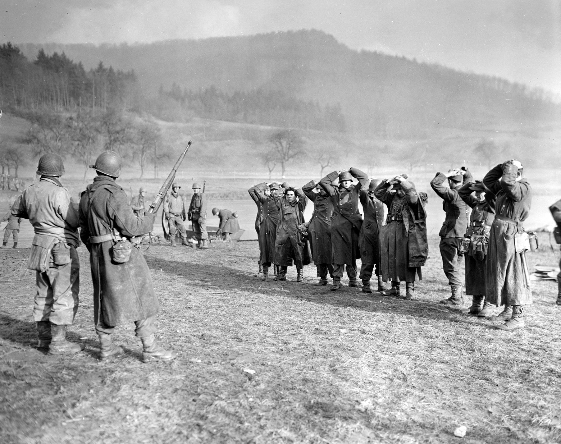 German prisoners, under the watch of American soldiers of the 5th Infantry Division, place their hands on their heads and await instructions. These Germans were taken prisoner near the city of Echternach, Luxembourg. 