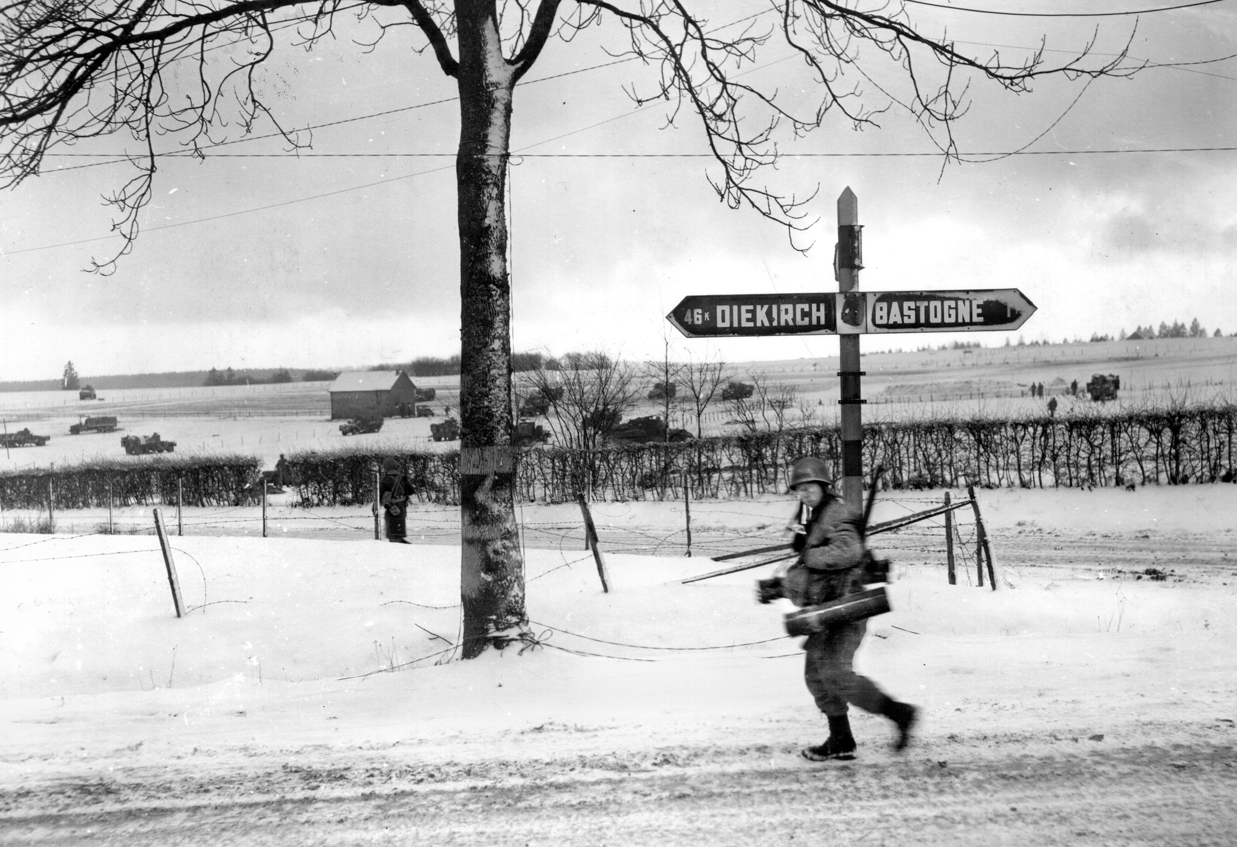 An American soldier of the 44th Armored Infantry Regiment, 6th Armored Division, carries a bazooka along a road near the outskirts of Bastogne, the embattled Belgian crossroads that was held against the Germans during the Battle of the Bulge. This infantryman is hurrying to join with tanks preparing to attack the Germans surrounding Bastogne.