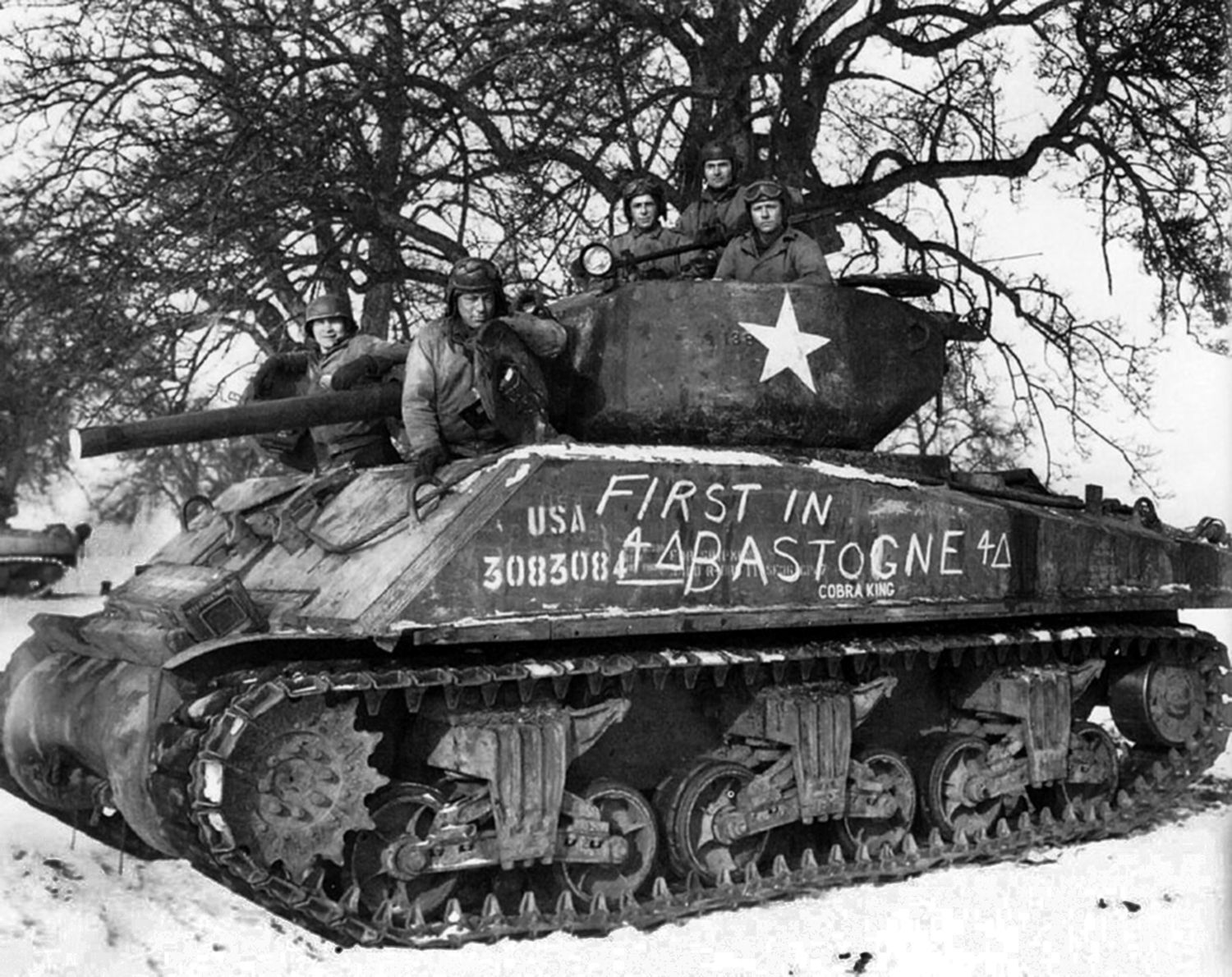 Lieutenant Charles Boggess’ M4 Sherman medium tank sits in the center of Bastogne with a triumphant message scrawled along its side. Crew members posed proudly for this photo shortly after Bastogne was liberated.