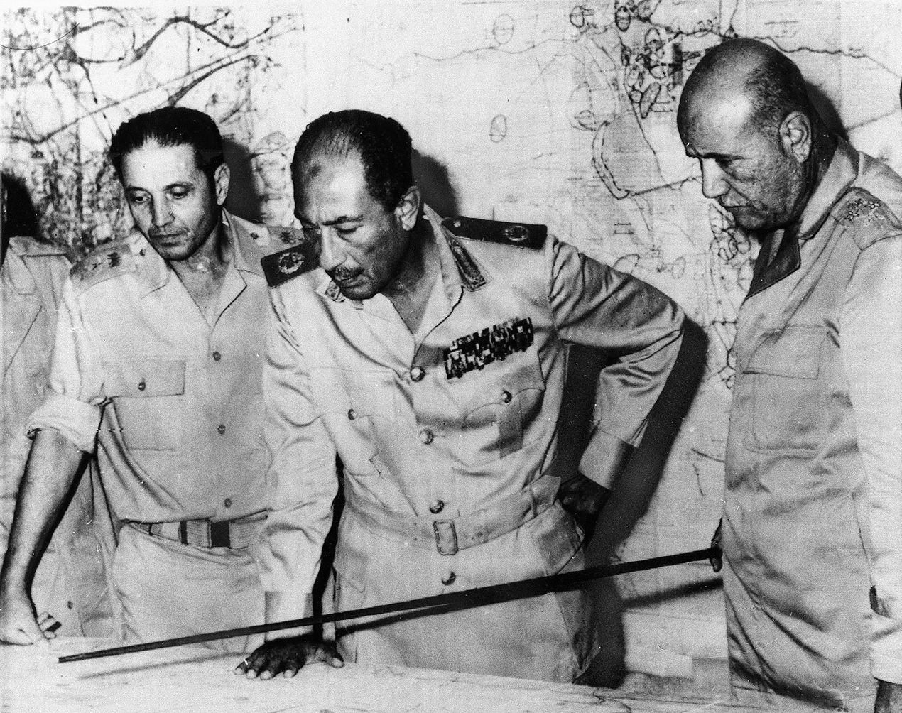 Egyptian President Anwar al-Sadat, right, looks at a situation map during fighting in the Sinai. Syrian president Hafez Al-Assad asked Sadat to attack Israel in the south to draw attention away from the Golan Heights, where Israeli forces had repelled his attack and invaded Syria. The Egyptian attack on the Sinai was also repelled.