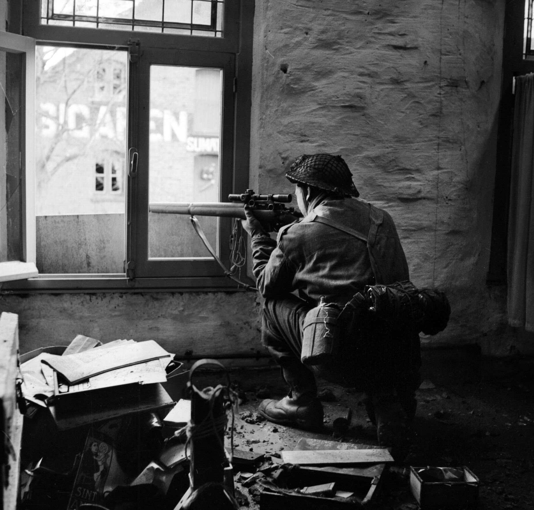  A British sniper from "C" Company, 5th Battalion, The Black Watch, searches for targets through his scope from his position in a ruined building in Gennep, Holland, 14 February 1945.