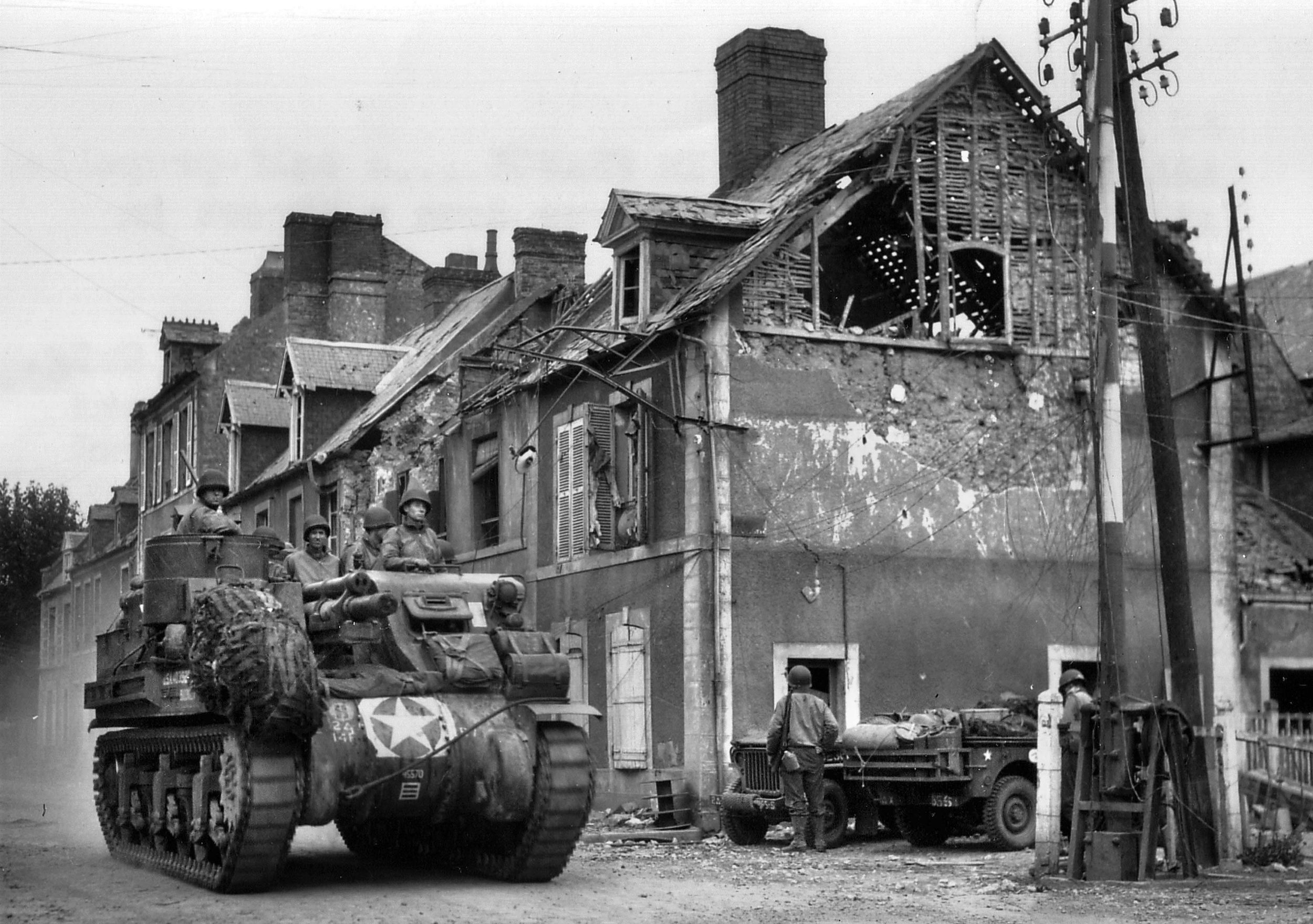 An American self-propelled gun rolls through a street in the French city of Carentan. As of June 11, 1944, General Hodges was monitoring the progress of the American effort to eject the Germans from the important road junction there. 