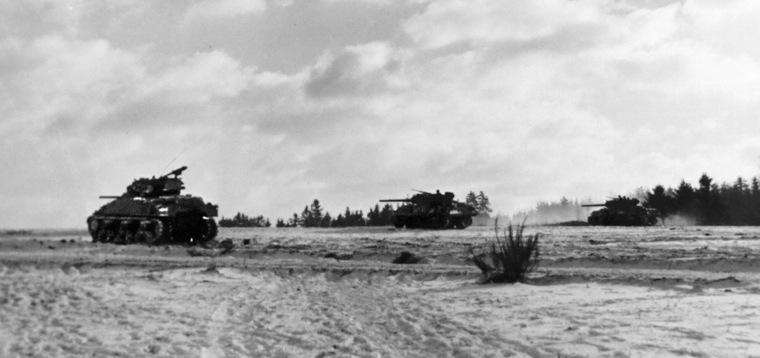 Photographed during an advance across open country at the height of the December 1944 Battle of the Bulge, an M4 Sherman medium tank and M10 tank destroyers proceed warily.