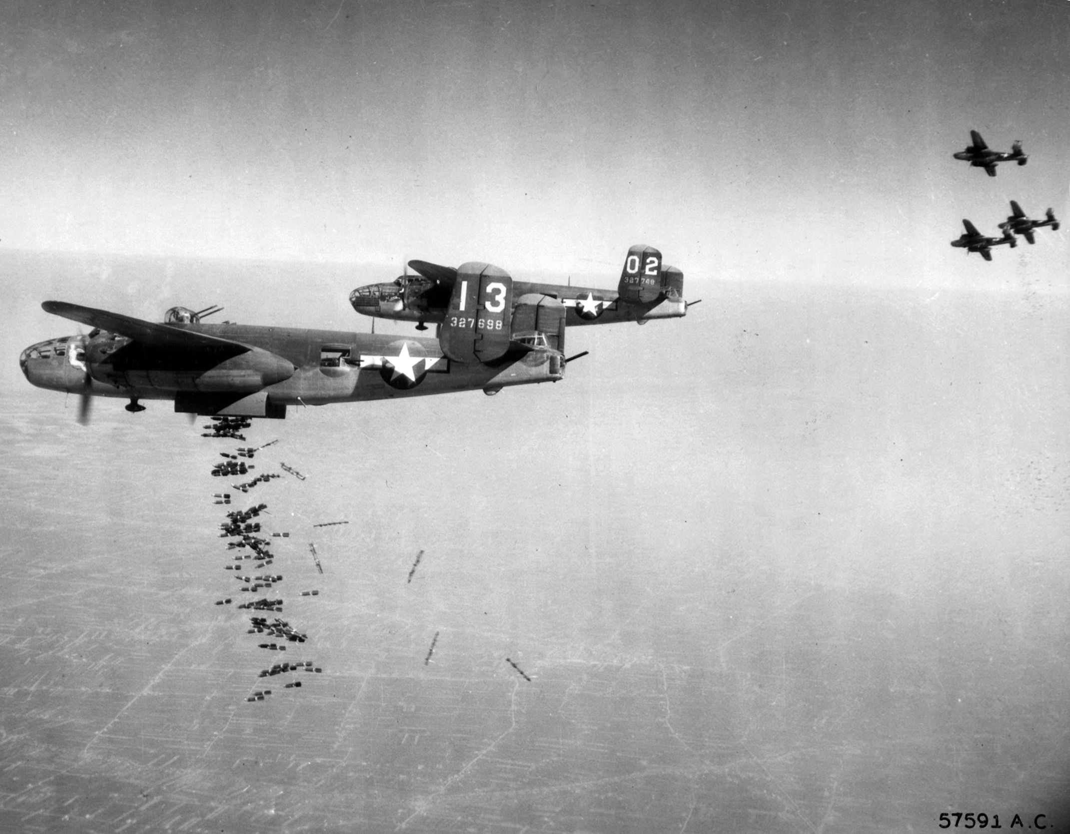 Supporting troops the British Eighth Army fighting the Germans near Lake Comacchio, Italy, B-25 Mitchell No. 13 of the U.S. Twelfth Air Force unleashes its bombload on Nazi troop concentrations below. 