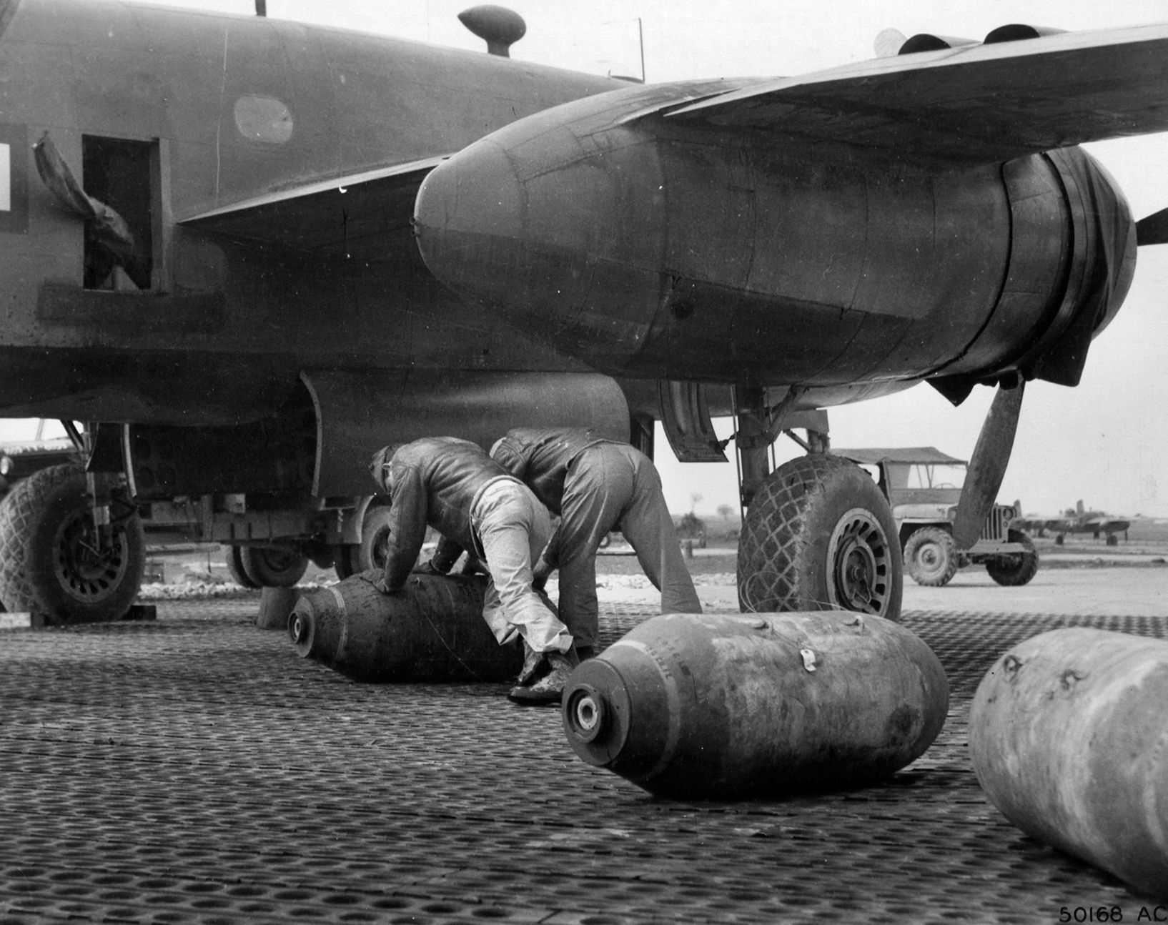 Ground crewmen roll a 1,000-pound bomb under the wing of a B-25 Mitchell bomber prior to lifting it into the bomb bay for a mission in Italy. The B-25s of the U.S. Twelfth Air Force provided extensive support for ground troops as they interdicted enemy supply routes along railroads and roadways in northern Italy.