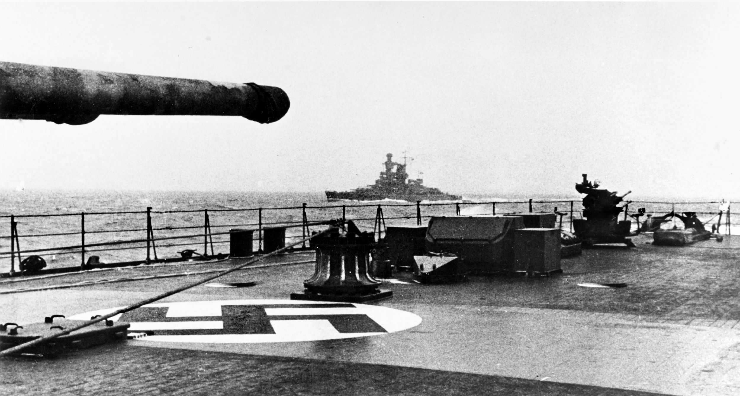 The Kriegsmarine pocket battleship Admiral Scheer is photographed from the deck of the heavy cruiser Prinz Eugen en route to Norway during Operation Cerberus—the “Channel Dash”—in February 1942. Aircraft recognition markings are visible on the deck of Prinz Eugen, as is a portable 20mm antiaircraft gun mounted further aft.