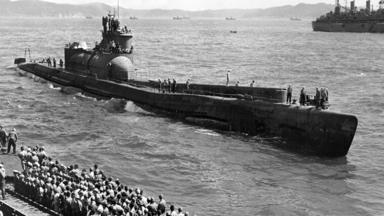 American sailors crowd the deck of the Japanese submarine I-14, tied up to the submarine tender USS Proteus. The object of their curiosity is the Japanese submarine I-400, which surrendered in Tokyo Bay in September 1945. Type B-1 submarines like the I-35 were the first Japanese cruisers with a surface range of 16,000 miles. The I-400 class, with a range of 43,123 miles, were the largest conventional submarines ever built. They were not eclipsed in size until the introduction of nuclear ballistic missile submarines in the 1960s.