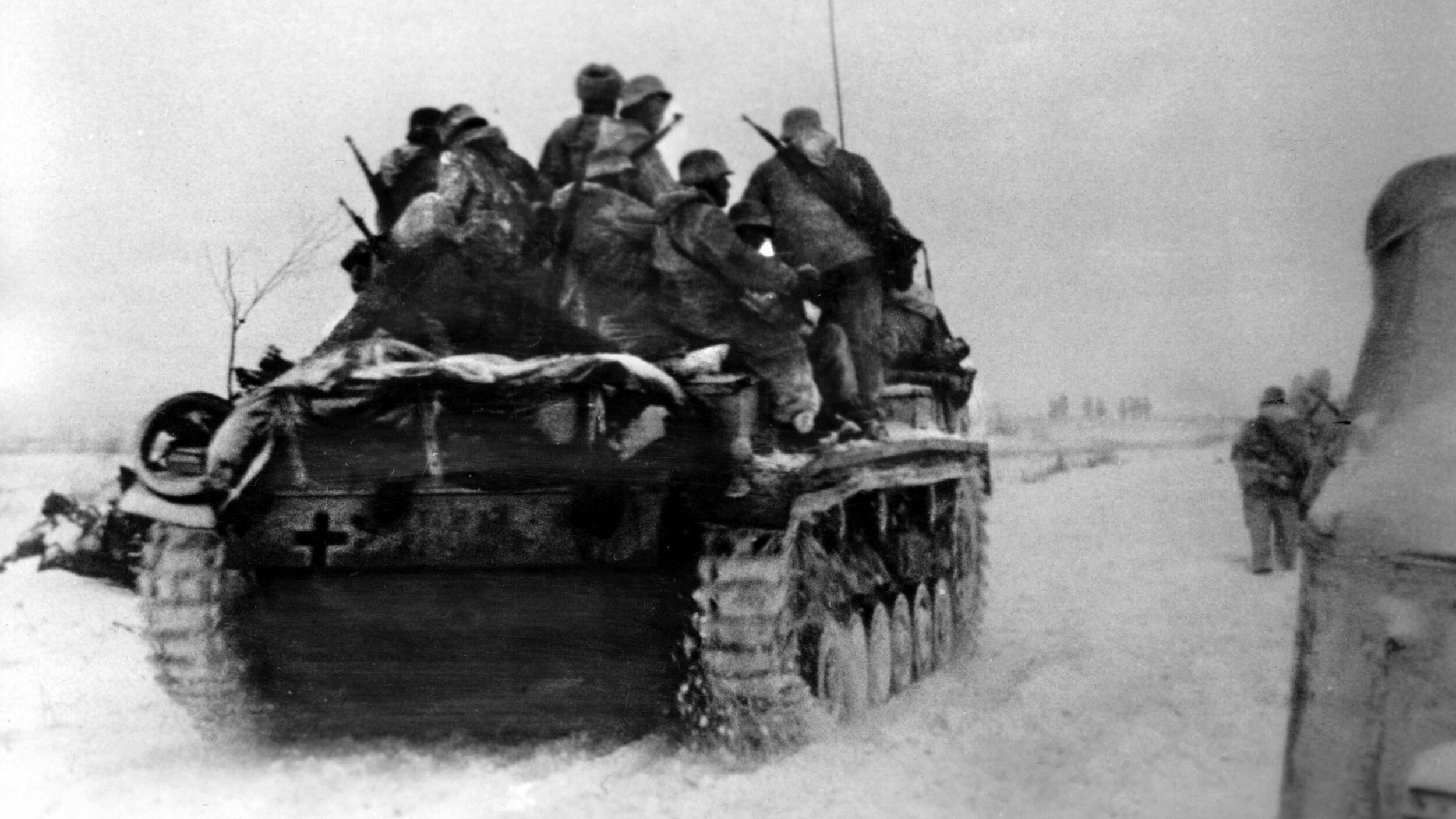 During the crucial Battle of Stalingrad, a German Sturmgeschutz III self-propelled assault gun rumbles across the snow covered landscape while Wehrmacht soldiers hitch a ride.