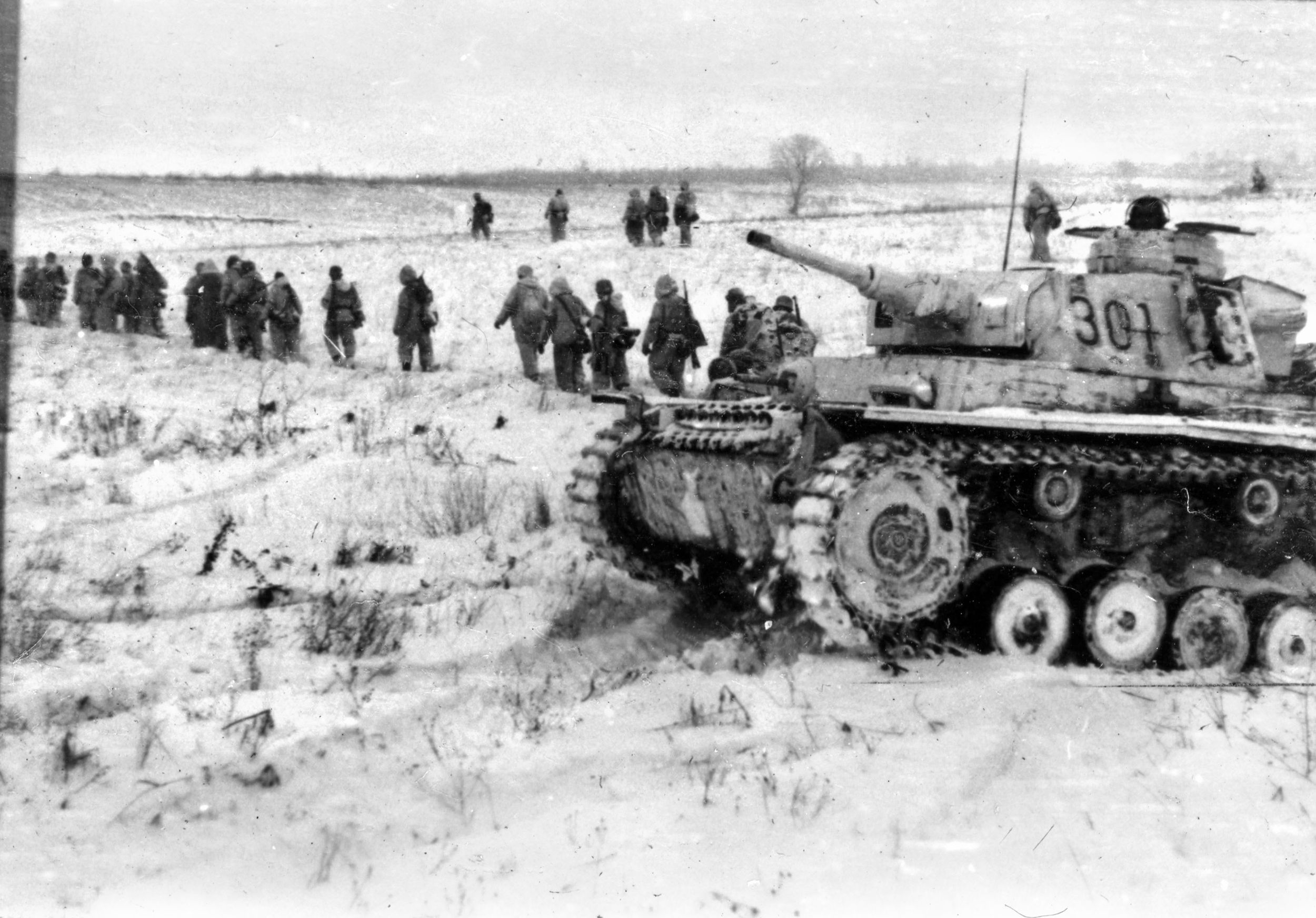 During the siege of Stalingrad in December 1942, Nazi panzergrenadiers trudge through snow and ice past one of their tanks that has paused momentarily. The bitter cold inhibited the operations of mechanized equipment.