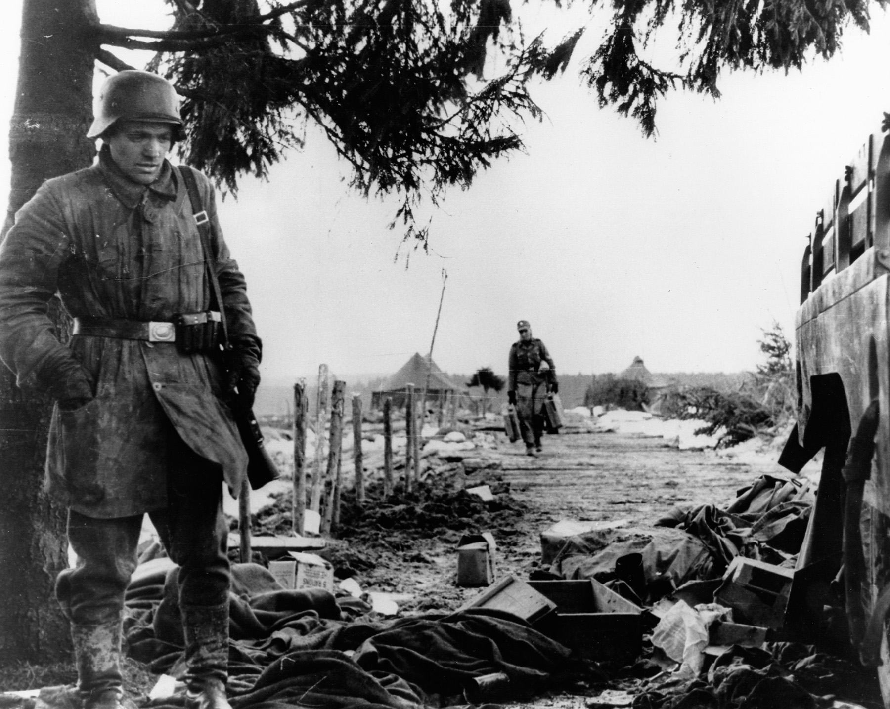 In another photo taken from a captured German camera, a soldier from the 18th Volksgrenadier Division, 5th Panzer Army examines scattered boxes and other items while scavenging through the camp of the U.S. 14th Cavalry Group.