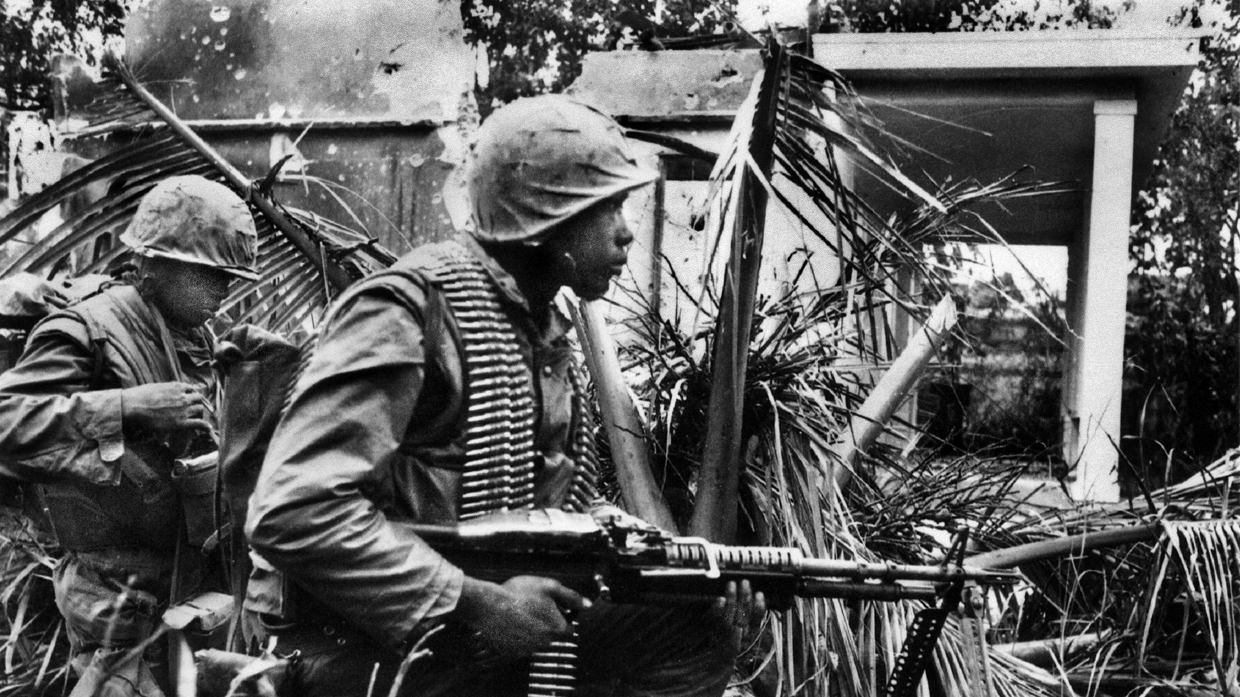 A member of the First Battalion, Fifth Marines with an M60 machine gun watches for North Vietnamese soldiers breaking cover in the battle for Hue, January 31, 1968.