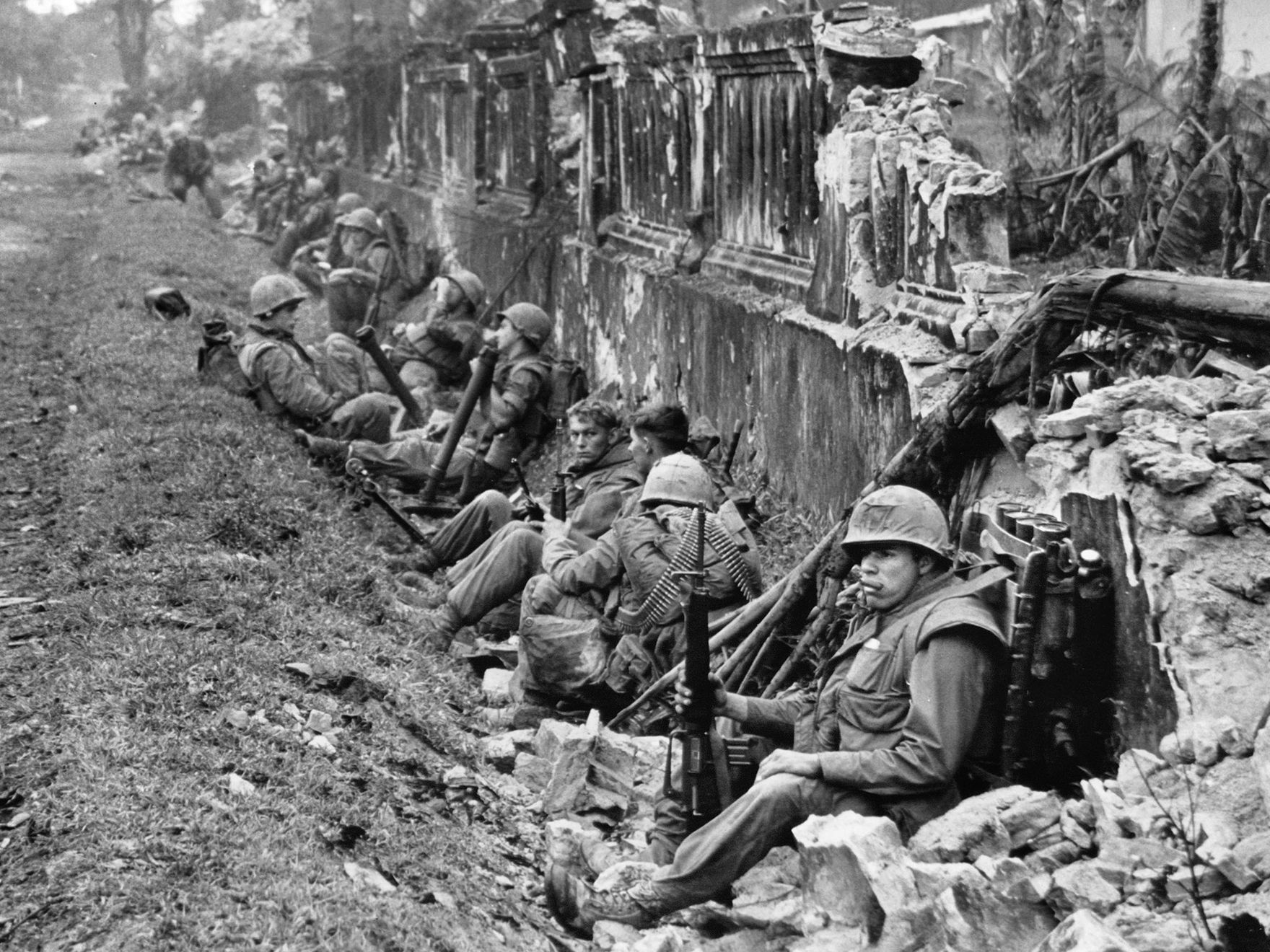 A unit of the 1st Battalion, 5th Marine Regiment, rests alongside a battered wall of Hue's imperial palace after a battle for the citadel in February 1968, during the Tet Offensive. 