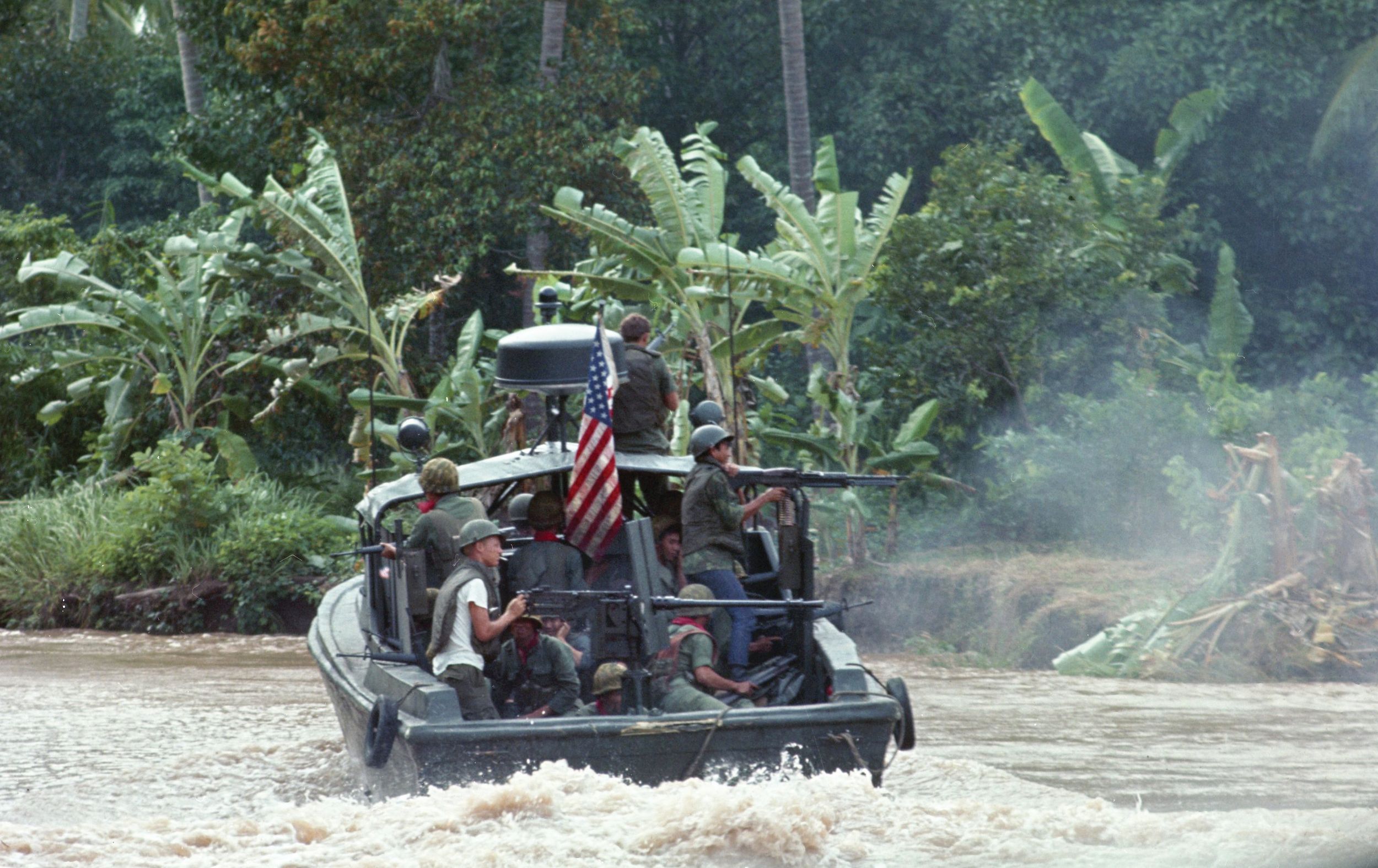 Crewman aboard a U.S. Navy river patrol boat (PBR) man their weapons during a river patrol mission in Vietnam.