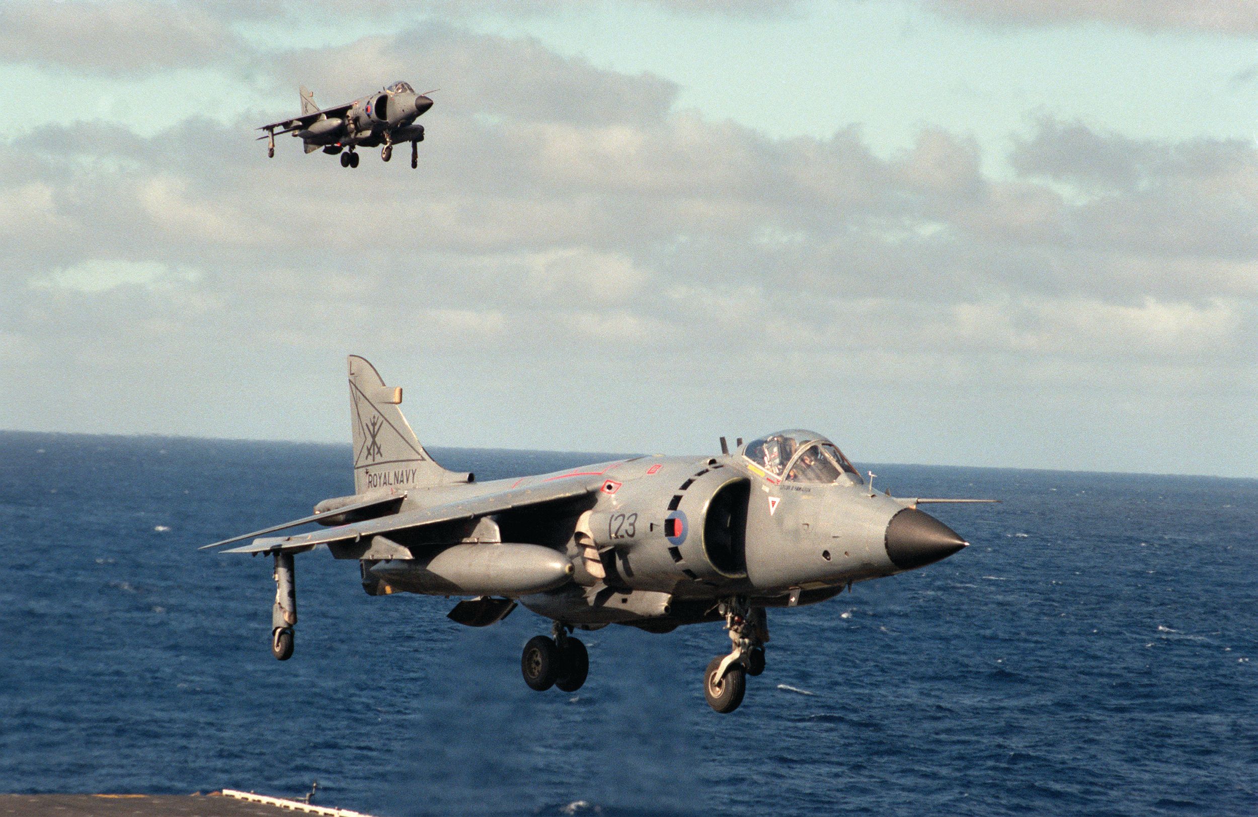 One British Royal Navy FRS.Mk 1 Sea Harrier hovers over the flight deck of the aircraft carrier USS Dwight D. Eisenhower as another approaches during an exercise in October 1984. 
