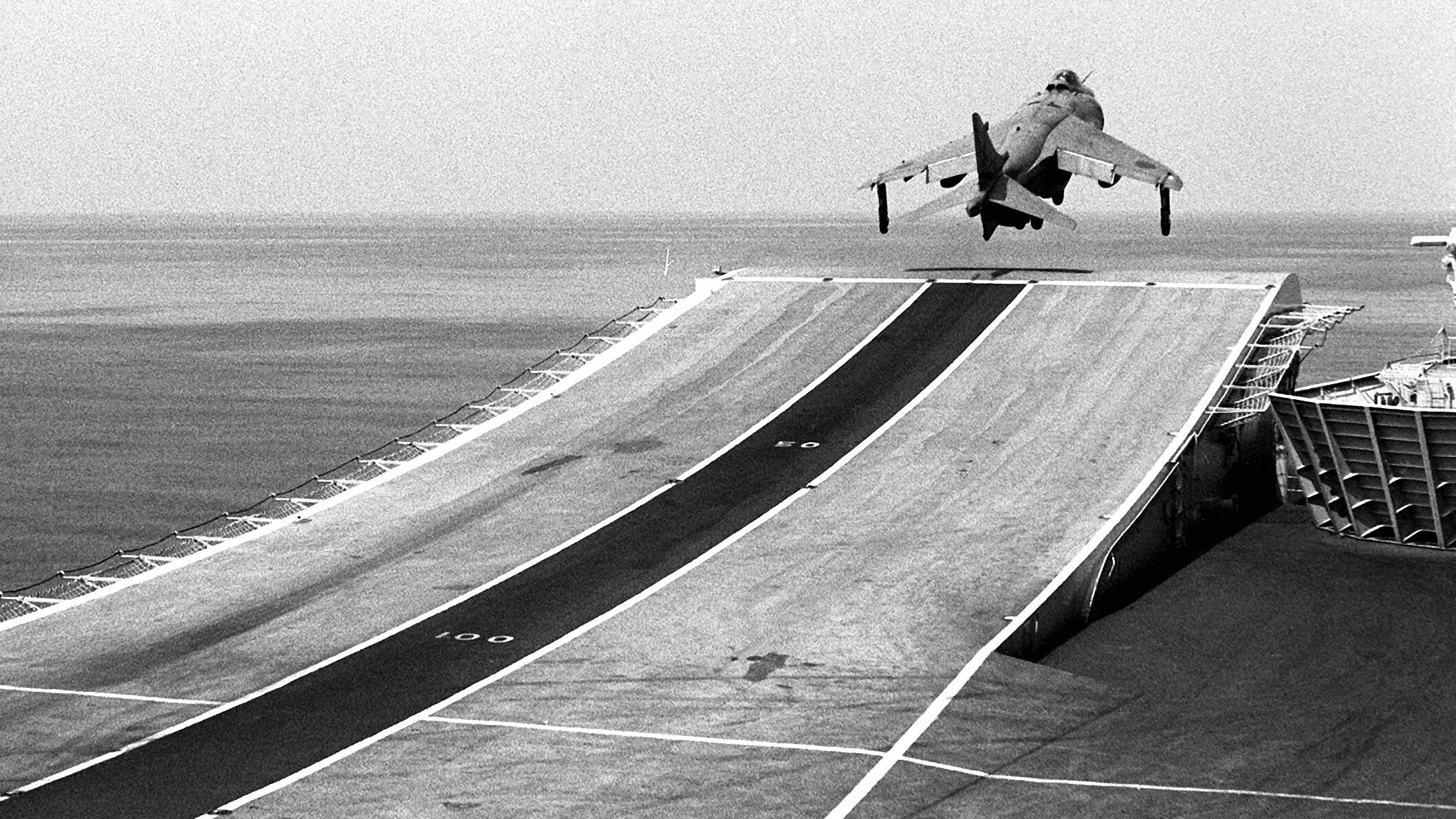 An FRS. Mark 1 Sea Harrier aircraft takes off from the flight deck of the British light aircraft carrier HMS Invincible during the NATO Southern Region exercise “Dragon Hammer” in 1990. An upward-curved ramp angled at 6.5 degrees allowed Sea Harriers to take off with a higher disposal payload. 