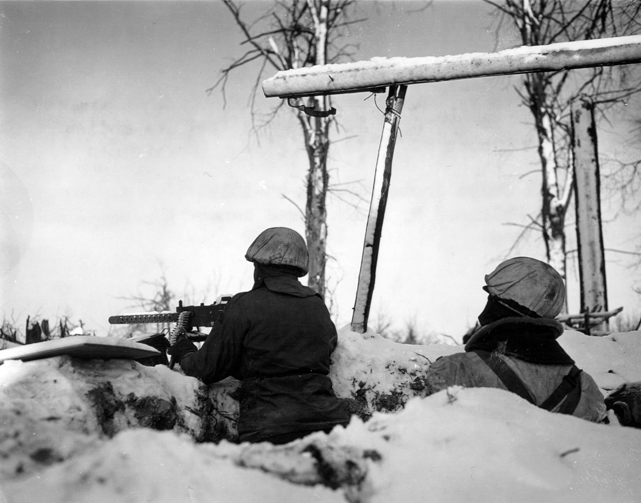 Camouflaged to blend into the winter landscape, two soldiers of the 7th Armored Division defend a roadblock near St. Vith on January 24, 1945.
