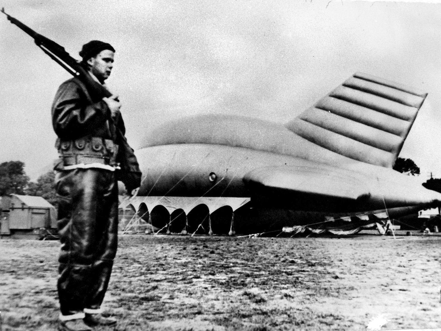 In northen California, an armed sentry in a leather flying suit guards a barrage balloon, which could be flown in case of a Japanese air attack.
