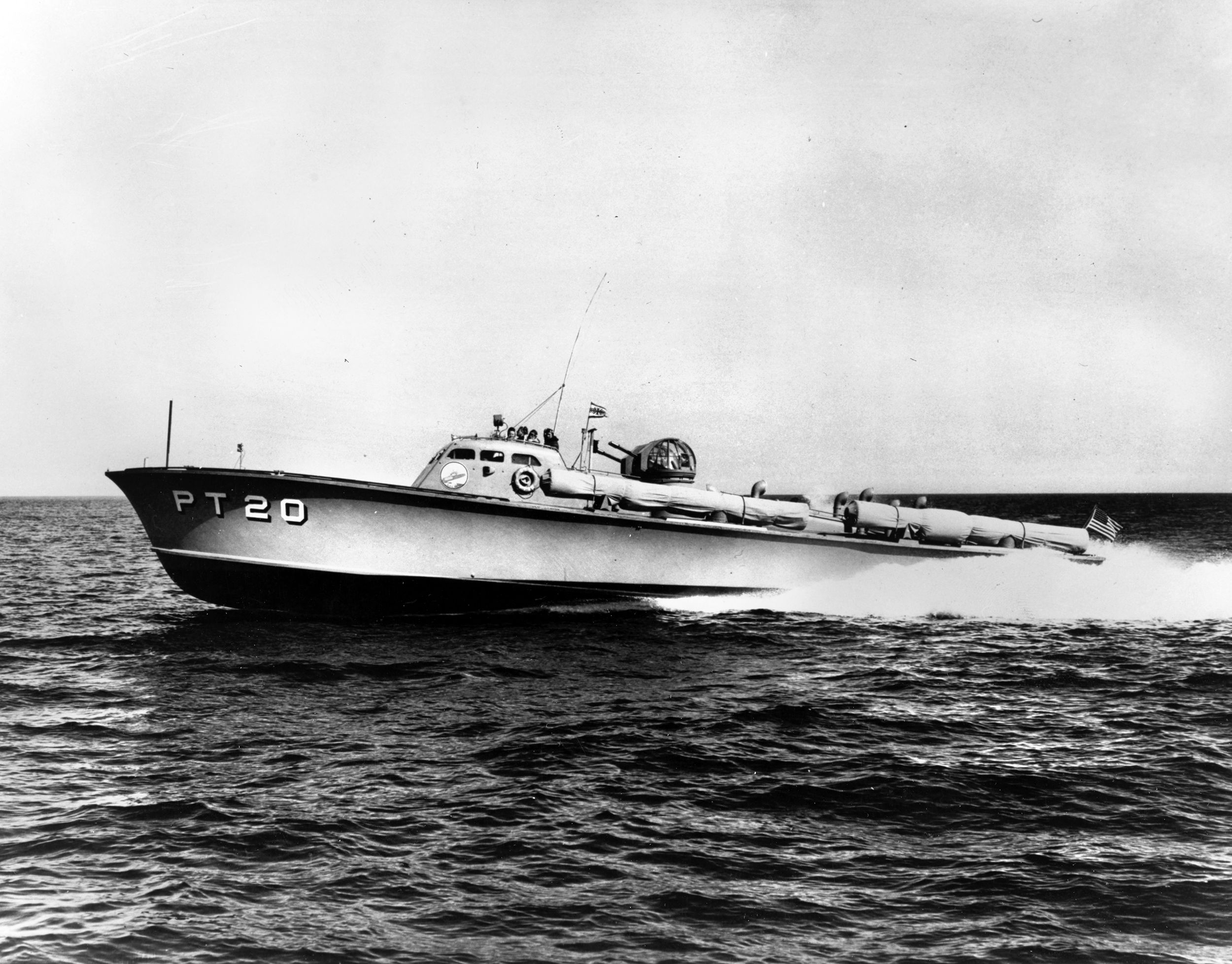 PT-20, built by the Electric Launch Company (Elco) of Bayonne, New Jersey, was the first vessel of Motor Torpedo Squadron One (MTBRon 1), formed on July 24, 1940, as the first operational command for U.S. Navy’s new Patrol Torpedo boats. Popularly believed to be made of plywood, PT boat hulls were constructed of two layers of one-inch mahogany planks with canvas (impregnated with glue or lead paint) between them. A planing hull and the horsepower of three Packard 3A-2500 V-12 liquid-cooled aircraft engines gave the small craft exceptional speed.