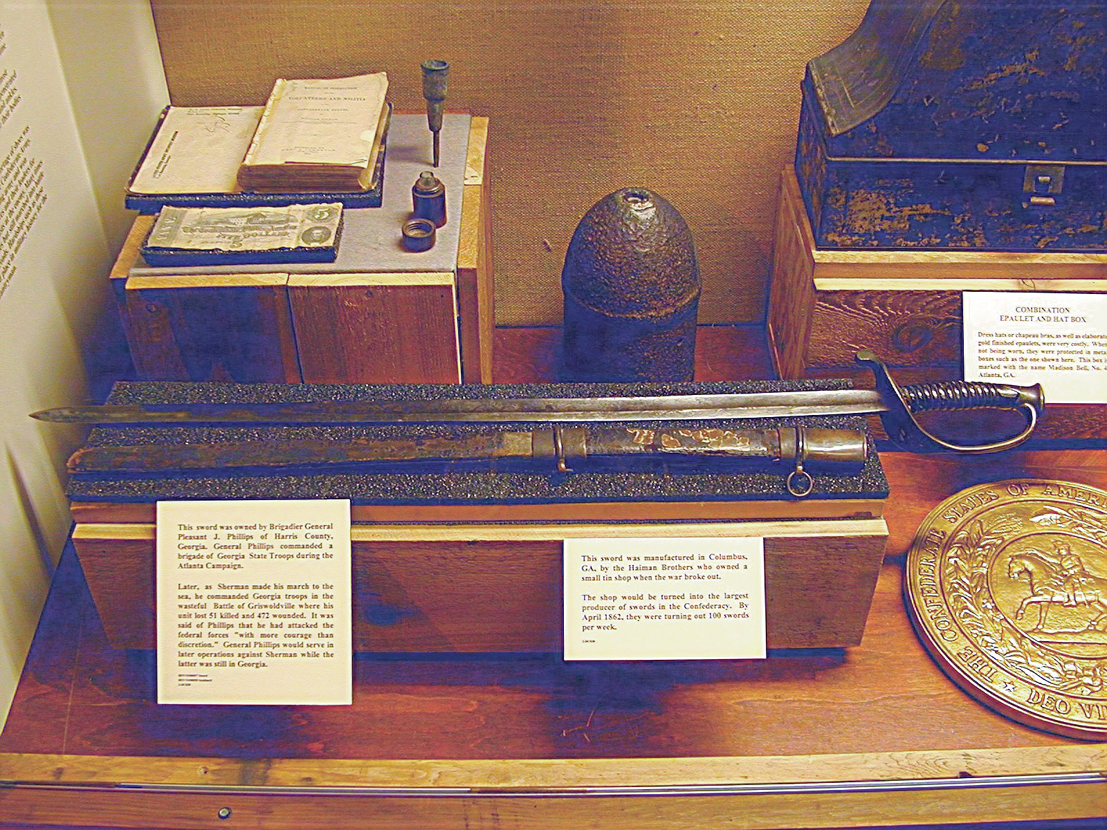 A display case of Confederate artifacts, including the sword of Georgia Brigadier General P.J. Phillips, an artillery shell, and a combination epaulet and hat box. 