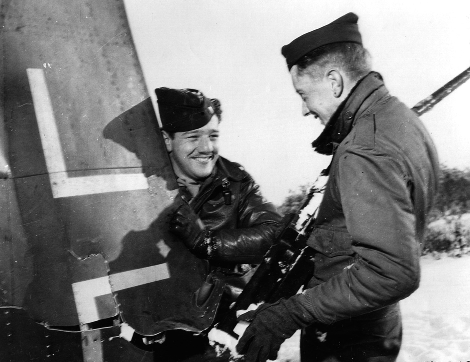 Second Lieutenant Melvin B. Paisley (left) and Second Lieutenant John J. Kennedy examine pieces of a Luftwaffe plane knocked out over Belgium in Operation Bodenplatte.