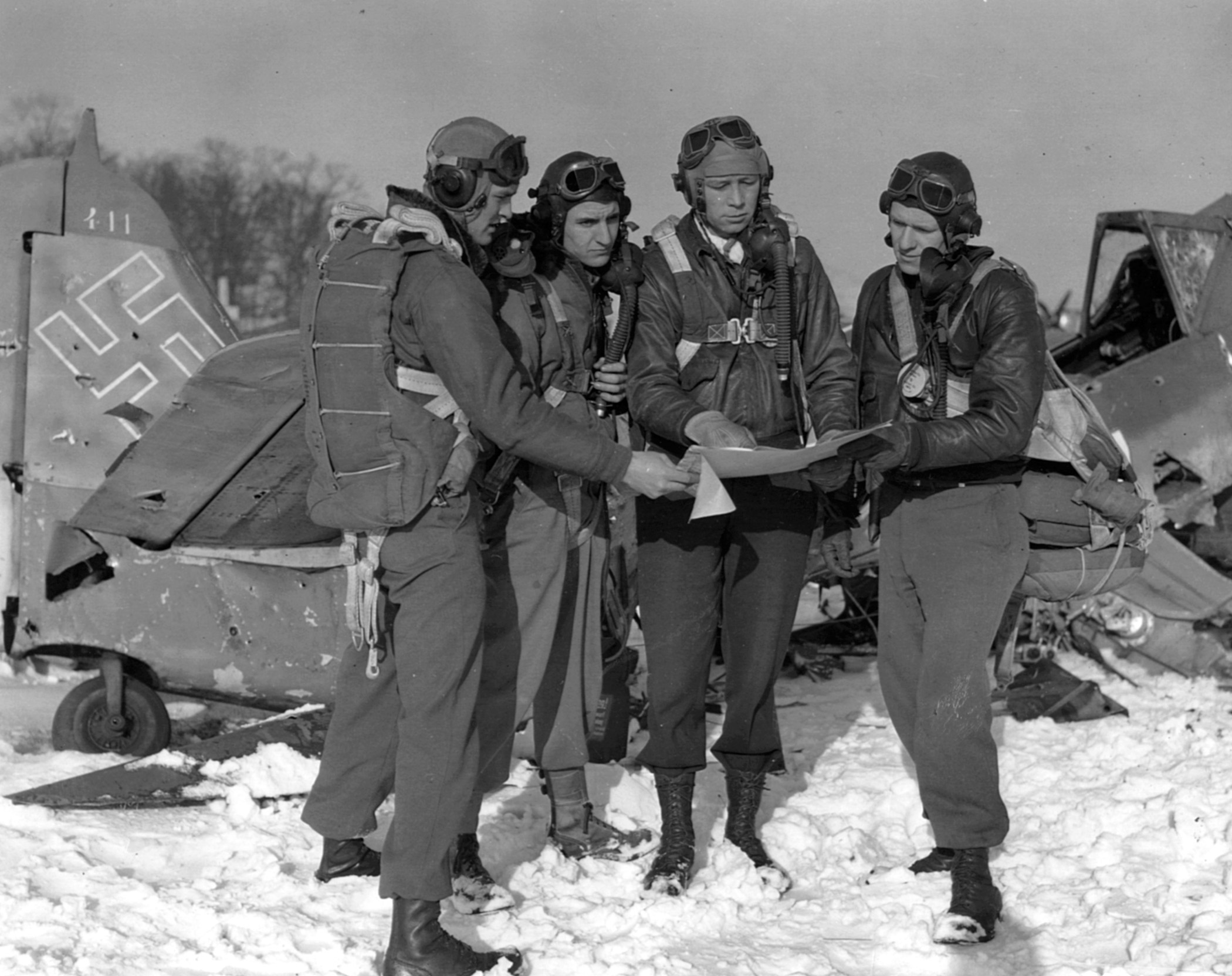 Colonel Ray J. Stecker, commander of the 365th Fighter Bomber Group (second from right), examines a map with pilots on the battlefield.