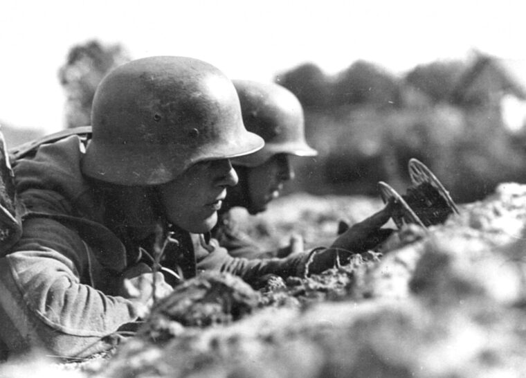 Working quickly, a duo of sniper-wary German combat engineers lay communications wire at the front.