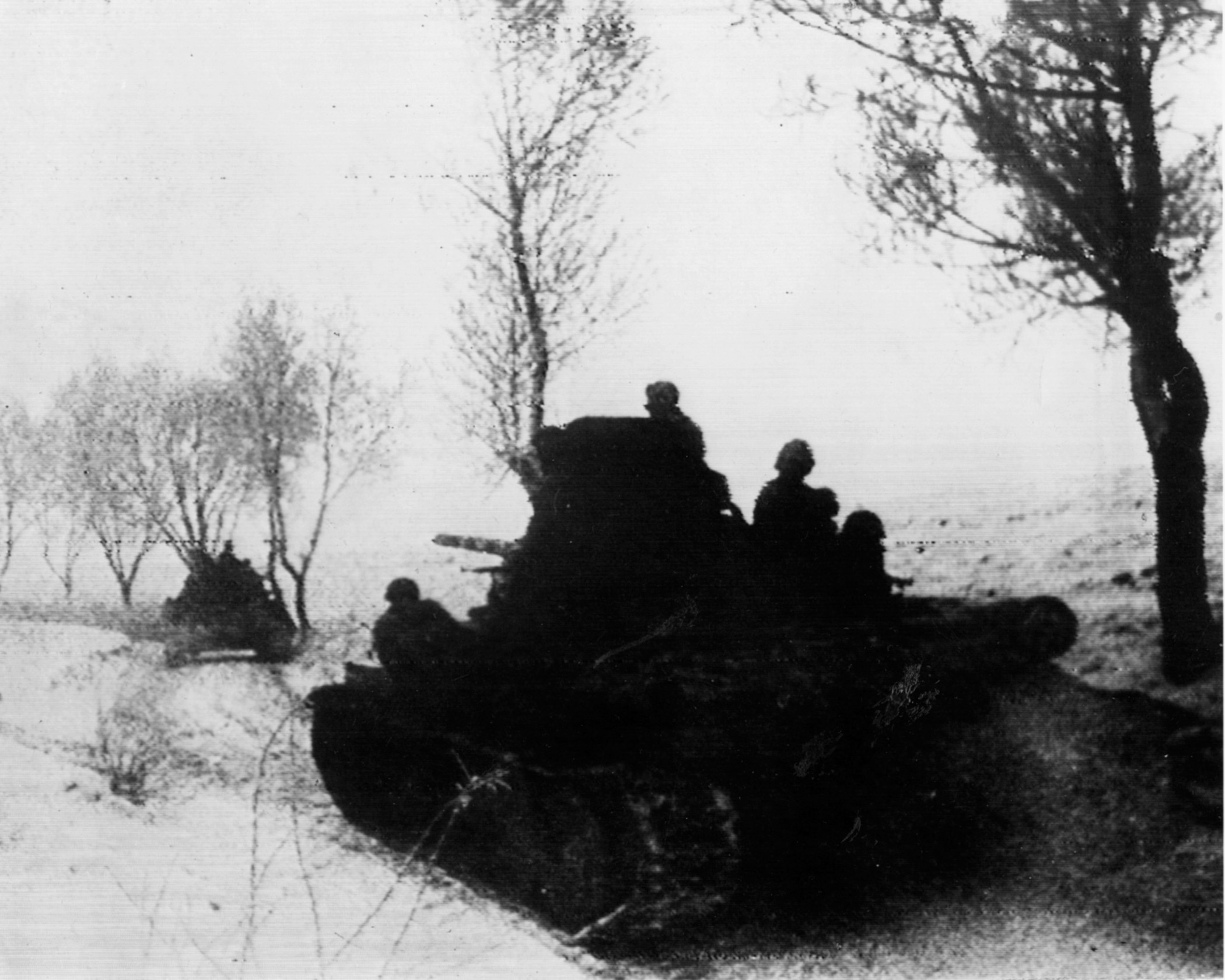 Red Army tanks loaded with infantrymen advance slowly across a snow-covered winter landscape.