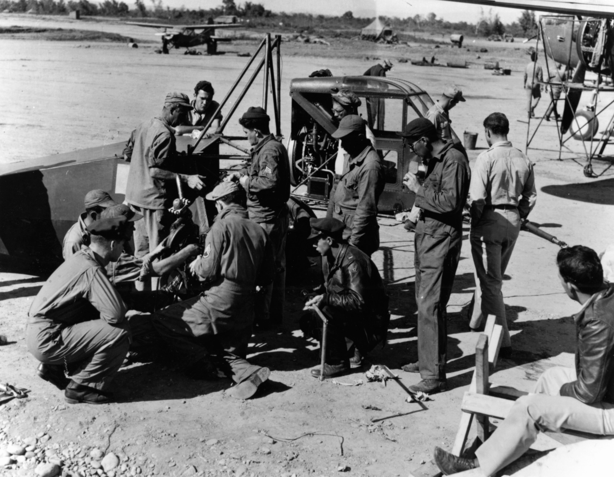 A group of mechanics assemble YR-4B helicopters in the China-Burma-India Theater. An L-5 Sentinel previously used for rescue missions sits in the background.