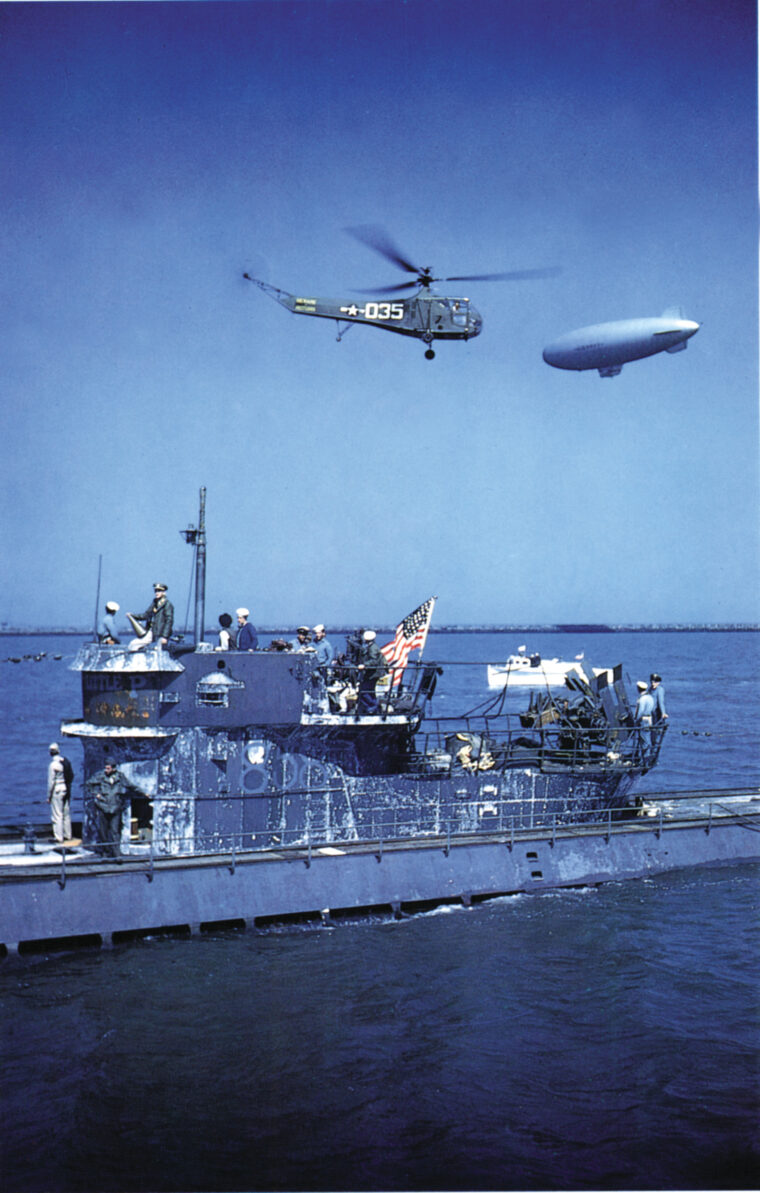 A helicopter hovers over the captured German submarine U-858 shortly after delivering U.S. Naval personnel to her conning tower.