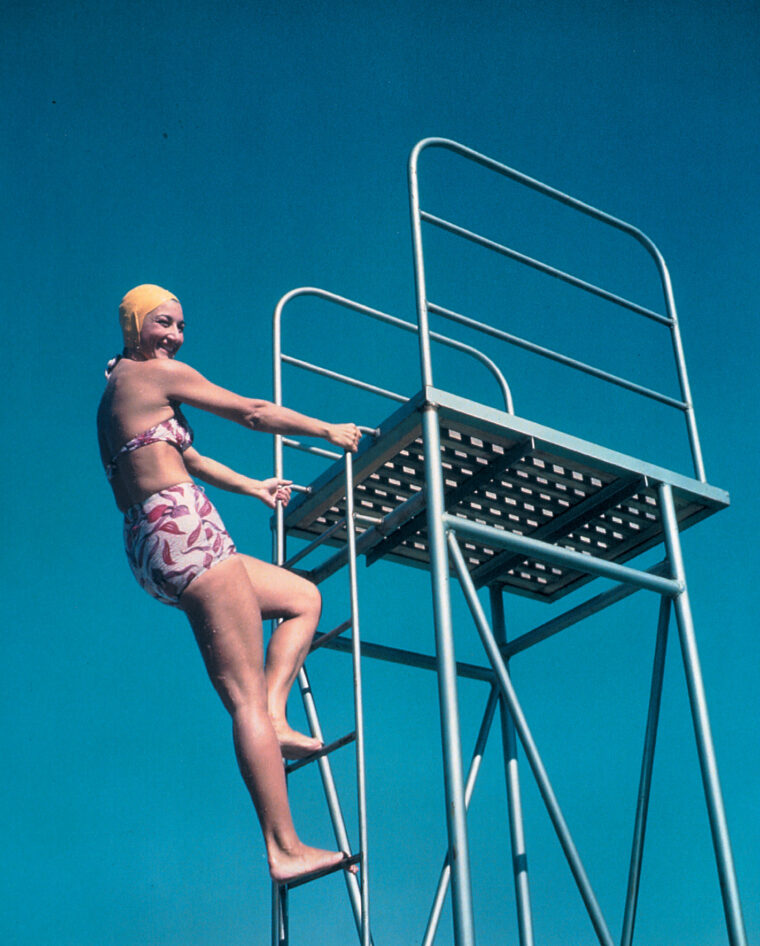 “Come up and see me sometime.” A Navy flight nurse climbs a diving platform during survival training at Alameda Naval Air Station in Florida. The swim cap was functional and made a nice fashion statement.