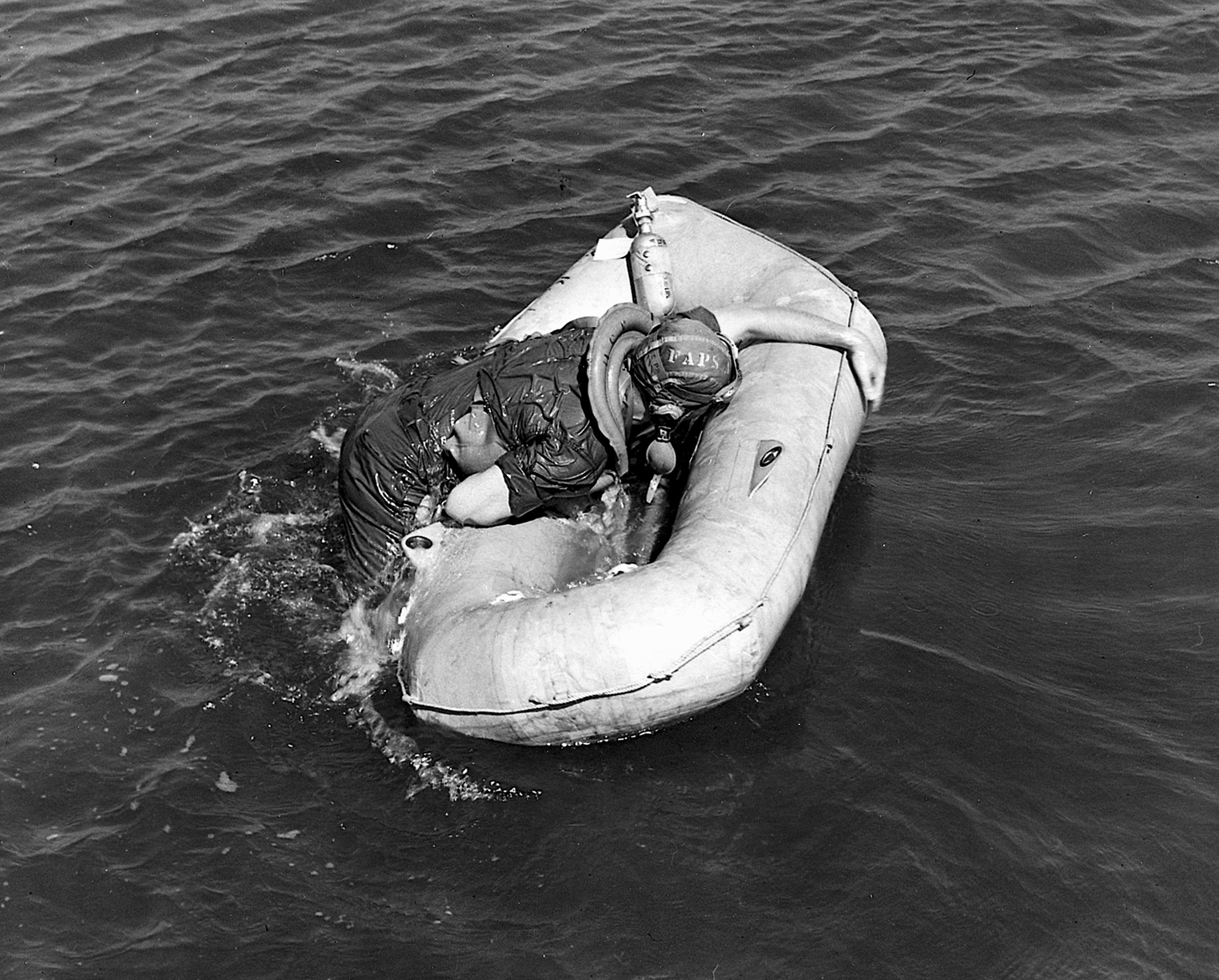 A Navy flier attempts the cumbersome task of boarding his one-man liferaft.