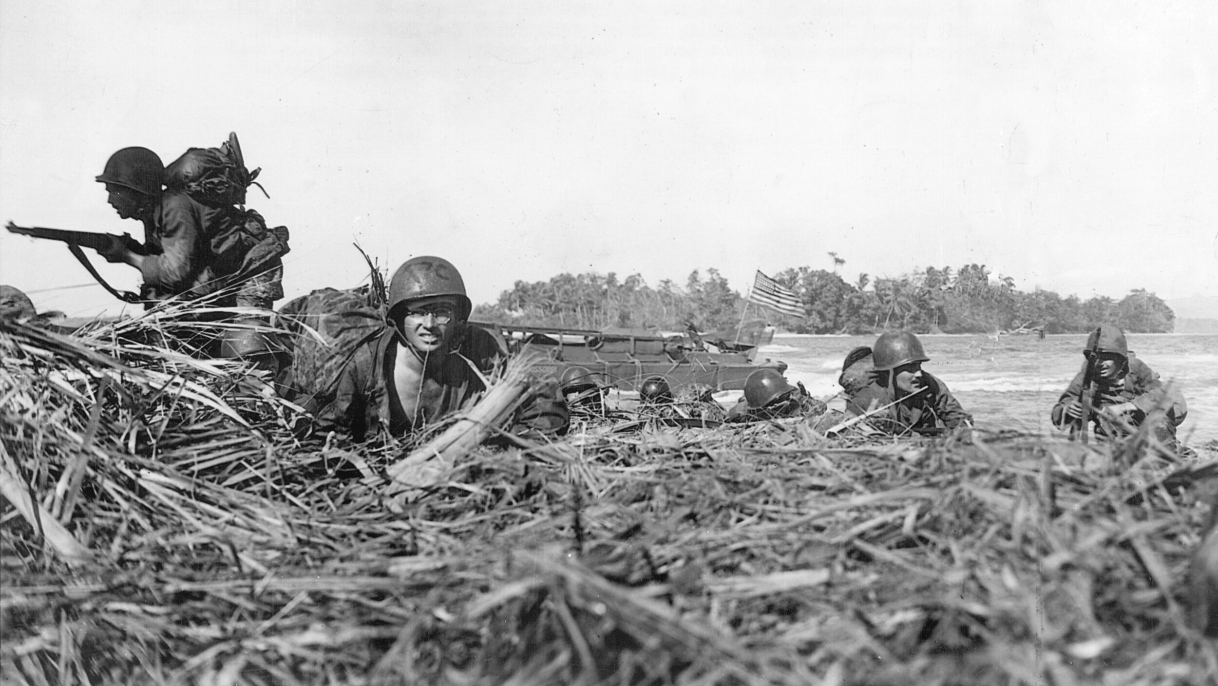 Under heavy Japanese fire, American soldiers seek safety behind a jumble of fallen trees and brush on the island of Wakde, May 17, 1944.