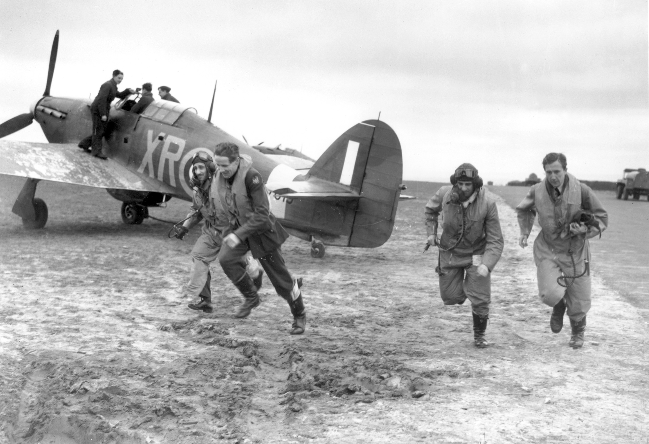 As one aviator is strapped into the cockpit of his Hawker Hurricane fighter, other pilots of the Eagle Squadron dash to the aircraft as an alarm is sounded during the Battle of Britain.